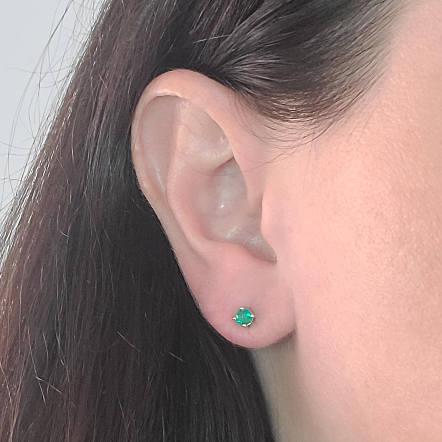18 Karat White Gold Small Stud Earrings Featuring 2 Round Emeralds Totaling Approximately 0.30 Carat. Pierced Post with Screw Back. Great For Children or a Second Piercing. Finished Weight is 0.8 Grams.