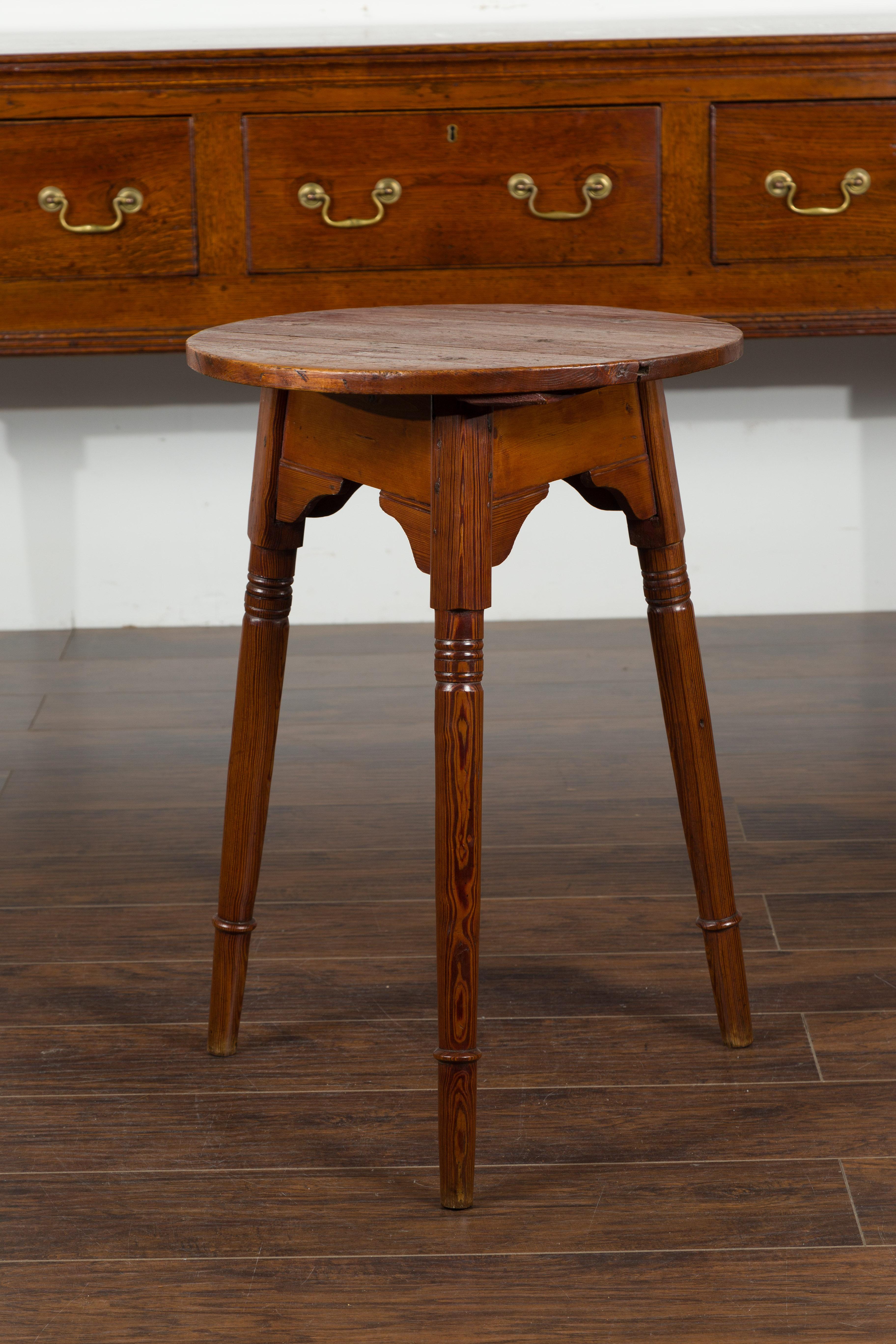 A small English pine cricket table from the mid-19th century, with carved apron and slender turned legs. Born in England during the second quarter of the 19th century, this pine cricket table features a circular top sitting above an apron carved on