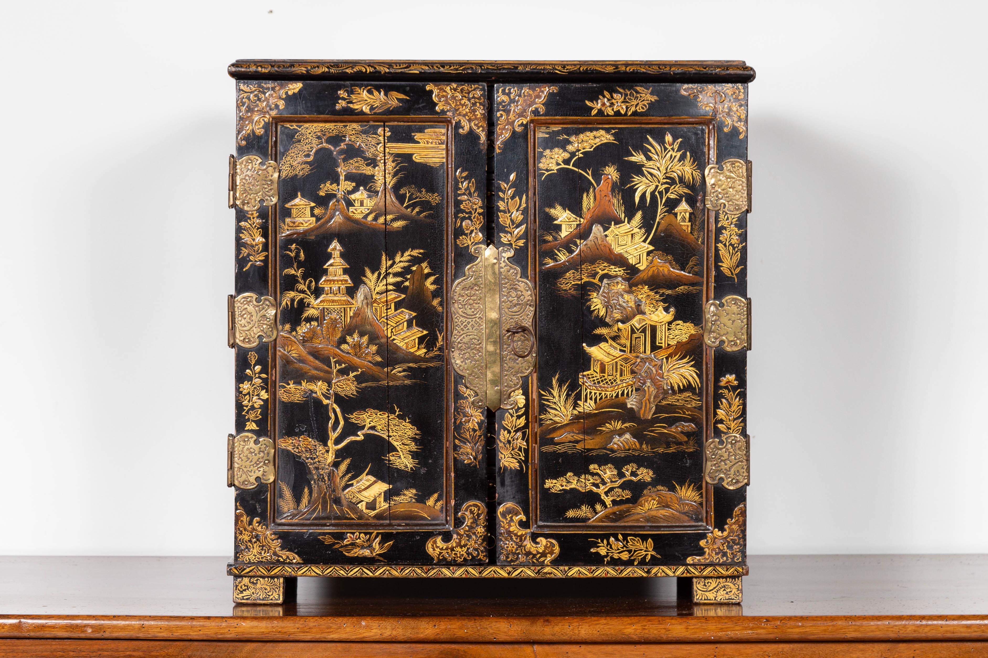 An English black and gold chinoiserie small cabinet from the late 19th century, with 10 inner drawers. Born in England during the last decade of the 19th century, this small cabinet features a black lacquered silhouette, adorned with a golden