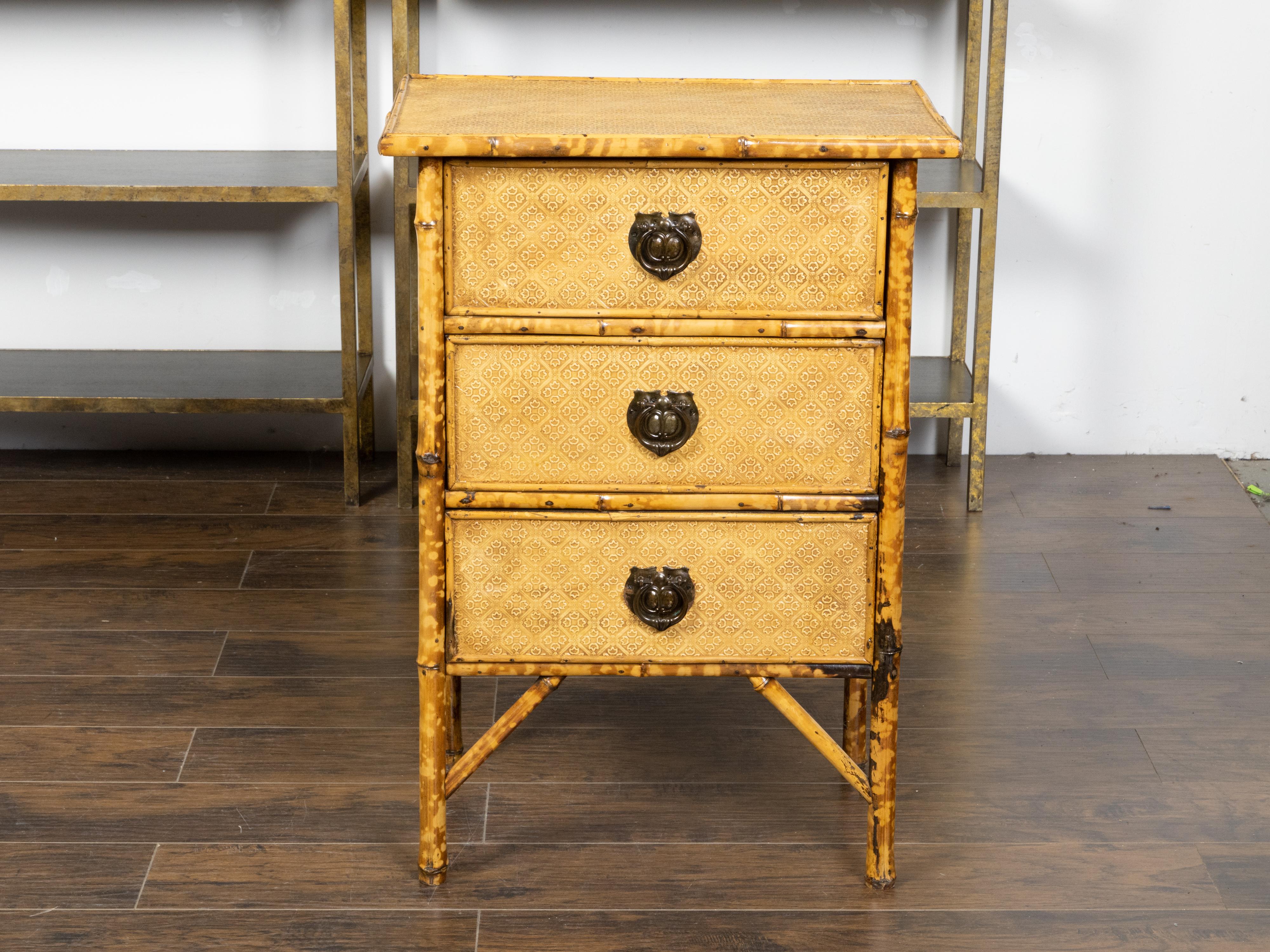 An English small bamboo chest from the early 20th century with floral décor, mottled effects, three drawers and metal hardware. Created in England during the Roaring Twenties, this small chest features a rectangular top adorned, along with the rest