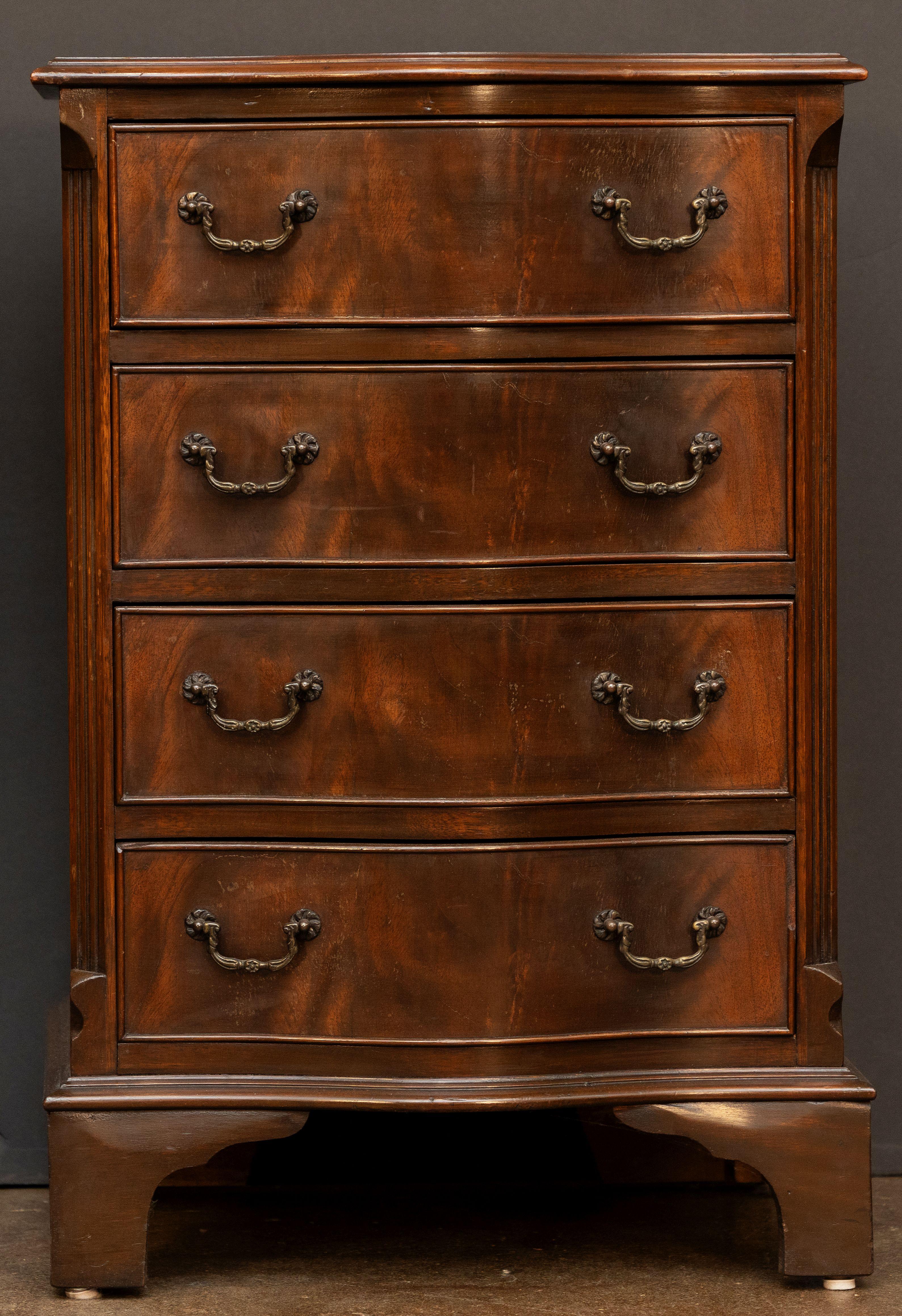 Una raffinata cassettiera o commode inglese in mogano patinato alla fiamma, caratterizzata da un piano a serpentina modellato su un fregio di quattro cassetti, angoli inclinati con un disegno a reticolo dall'alto alla base, ogni cassetto con tiretti
