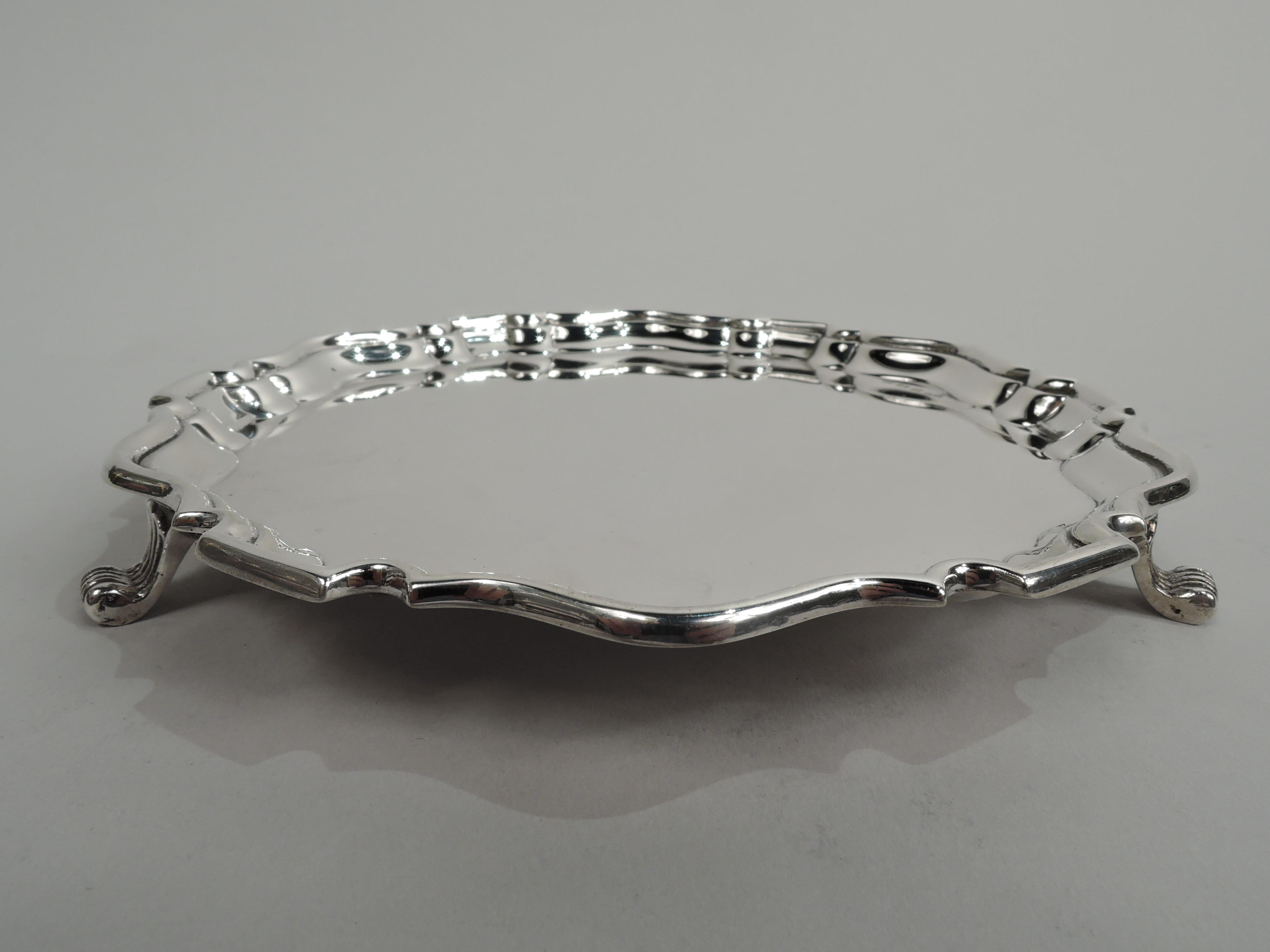 George VI sterling silver salver. Made by EW Haywood in Birmingham in 1939. Round with curvilinear piecrust rim. Three fluted and tapering scroll supports. Classic Georgian Chippendale style. Fully marked. Weight: 4 troy ounces.