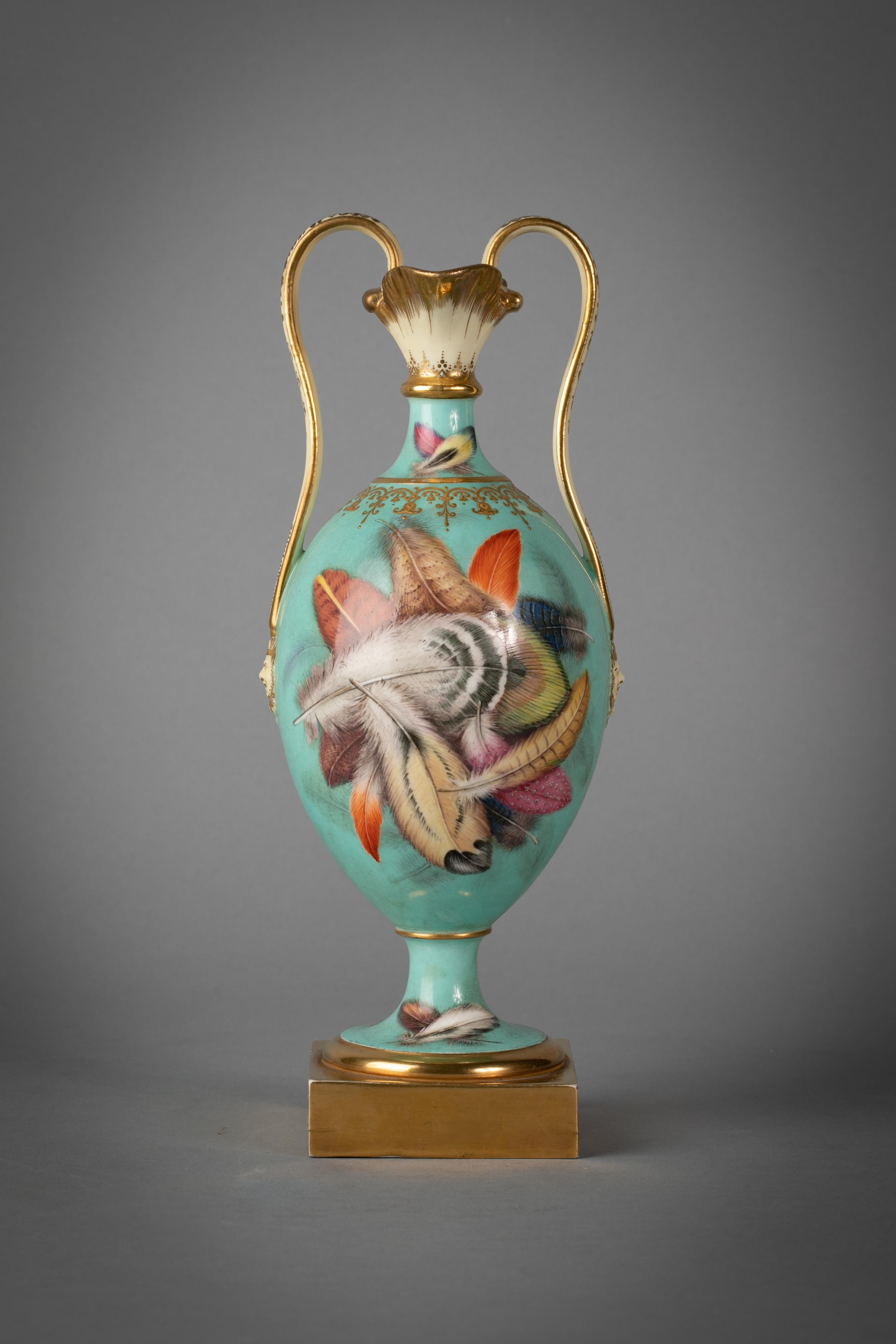 Twin handled double lipped vase. Finely painted with feathers and handles terminating with molded masks.