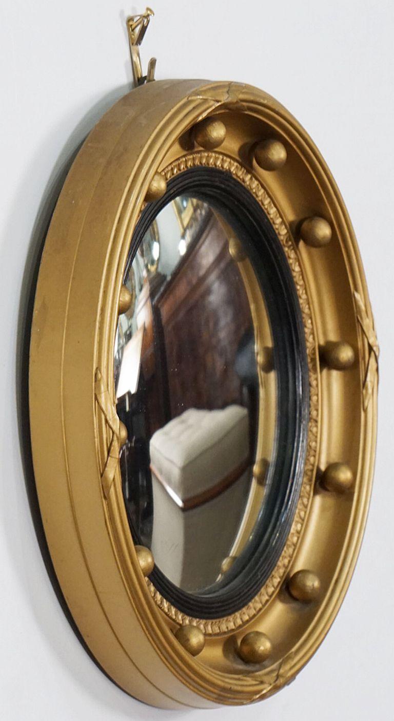 A small fine English round or circular convex mirror featuring a Regency design of a moulded gilt frame and ebonized trim, with gilt balls around the circumference.

Dimensions: Diameter 11 7/8 inches x Depth 1 7/8 inches