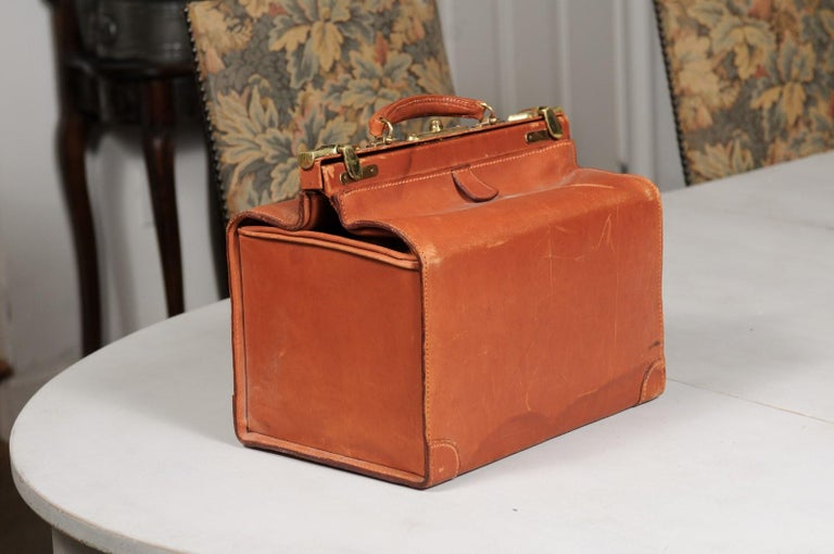 An English vintage small leather case from the mid 20th century, with brass accents, signed Carell. Created in England during the 20th century, this small leather case is made of brown leather accented with brass hardware. Showcasing a top handle,