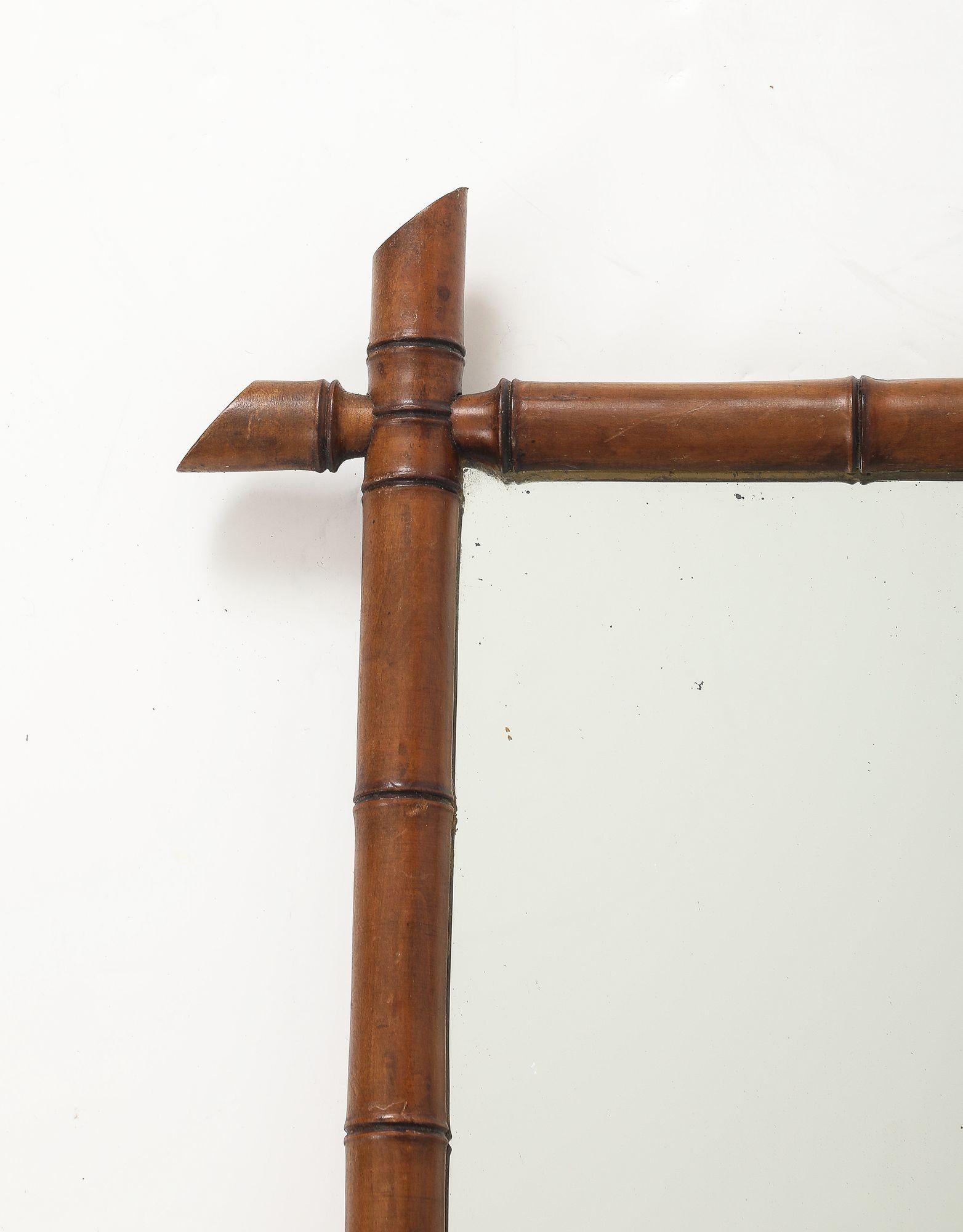 Ce charmant miroir anglais des années 1940 présente un cadre en faux bambou finement sculpté avec une patine riche et chaude qui imite magnifiquement l'aspect naturel du bambou. Le miroir a conservé sa plaque de verre d'origine, qui a légèrement
