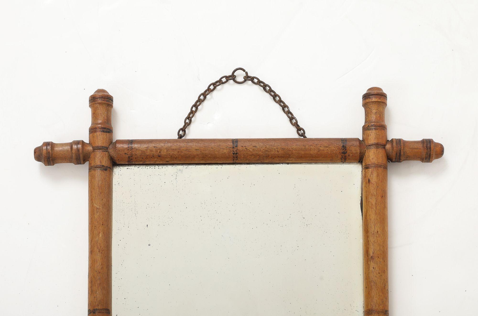 Ce charmant miroir anglais des années 1940 présente un cadre en faux bambou finement sculpté avec une patine riche et chaude qui imite magnifiquement l'aspect naturel du bambou. Le miroir a conservé sa plaque de verre d'origine, qui a légèrement