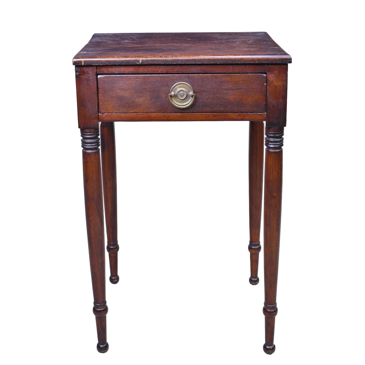 A small Sheraton work table from the Federal period in mahogany with turned legs and one drawer with original round brass plate and pull. Original finish has amalgamated, offering a deep rustic patina, American, circa 1800. Perfect as a small end