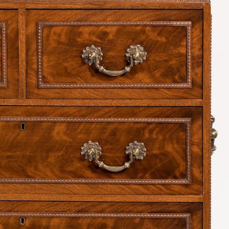 A small fine quality Georgian style mahogany cabinet on stand with two short and three long drawers, decorated with flame veneers and beading, with the original handles to the drawers and sides, the stand comprising double columns, English, circa