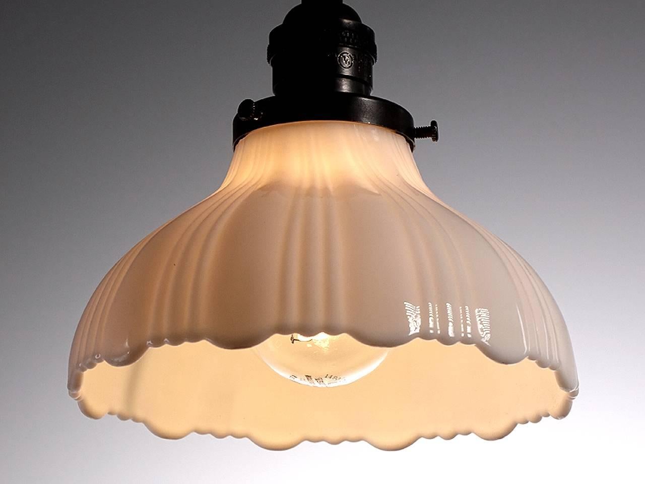 Softly curved bell shaped pendants are a Classic. They feel at home with any style decor. This example is an extra heavy thick-thin pattern in cast milk glass with a scalloped edge. The pattern has three thin ribs and one wide. The lamps are priced