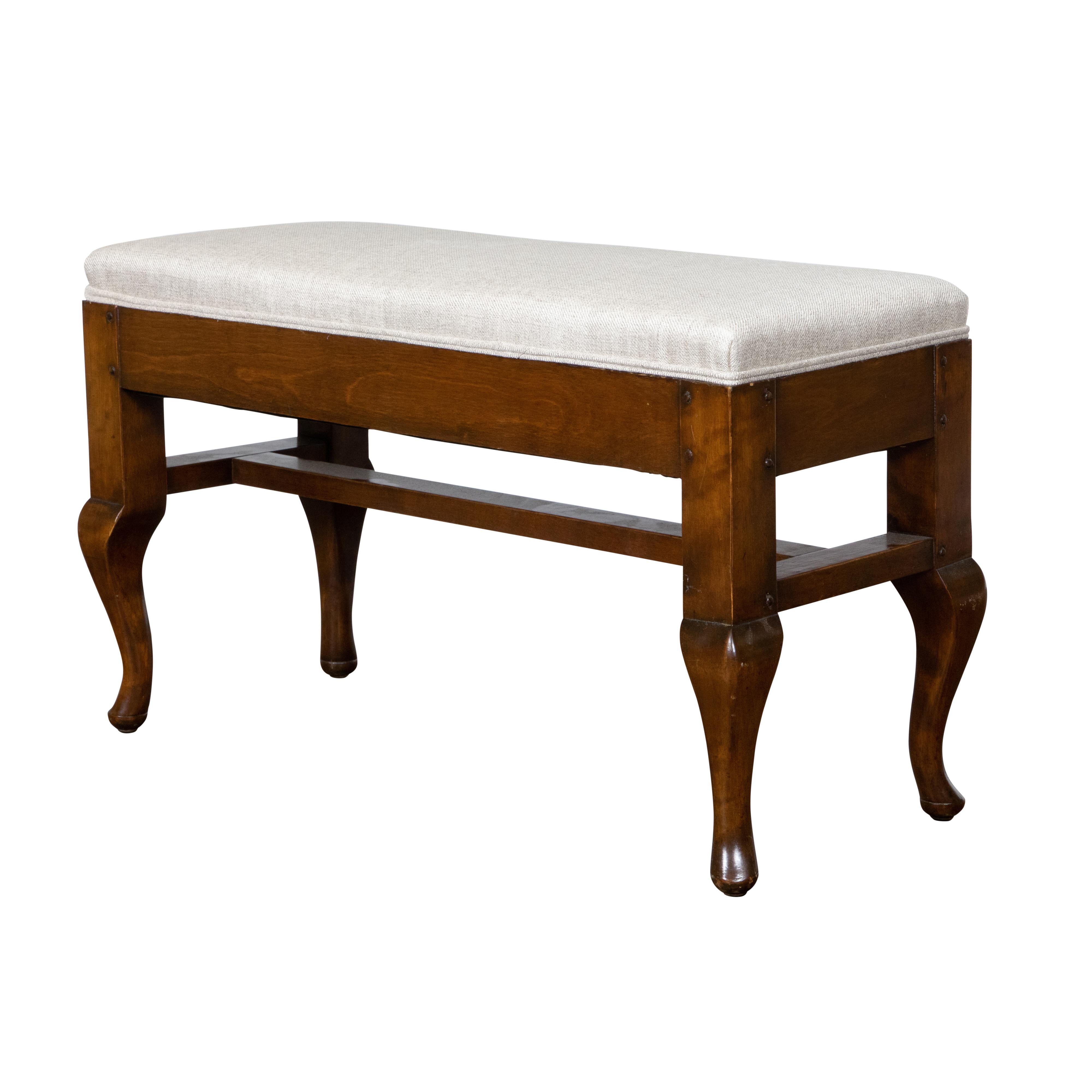 A small French wooden bench from the early 19th century, with curving legs, H-Form cross stretcher and new upholstery. Created in France during the early years of the 19th century, this wooden bench features a rectangular top newly and