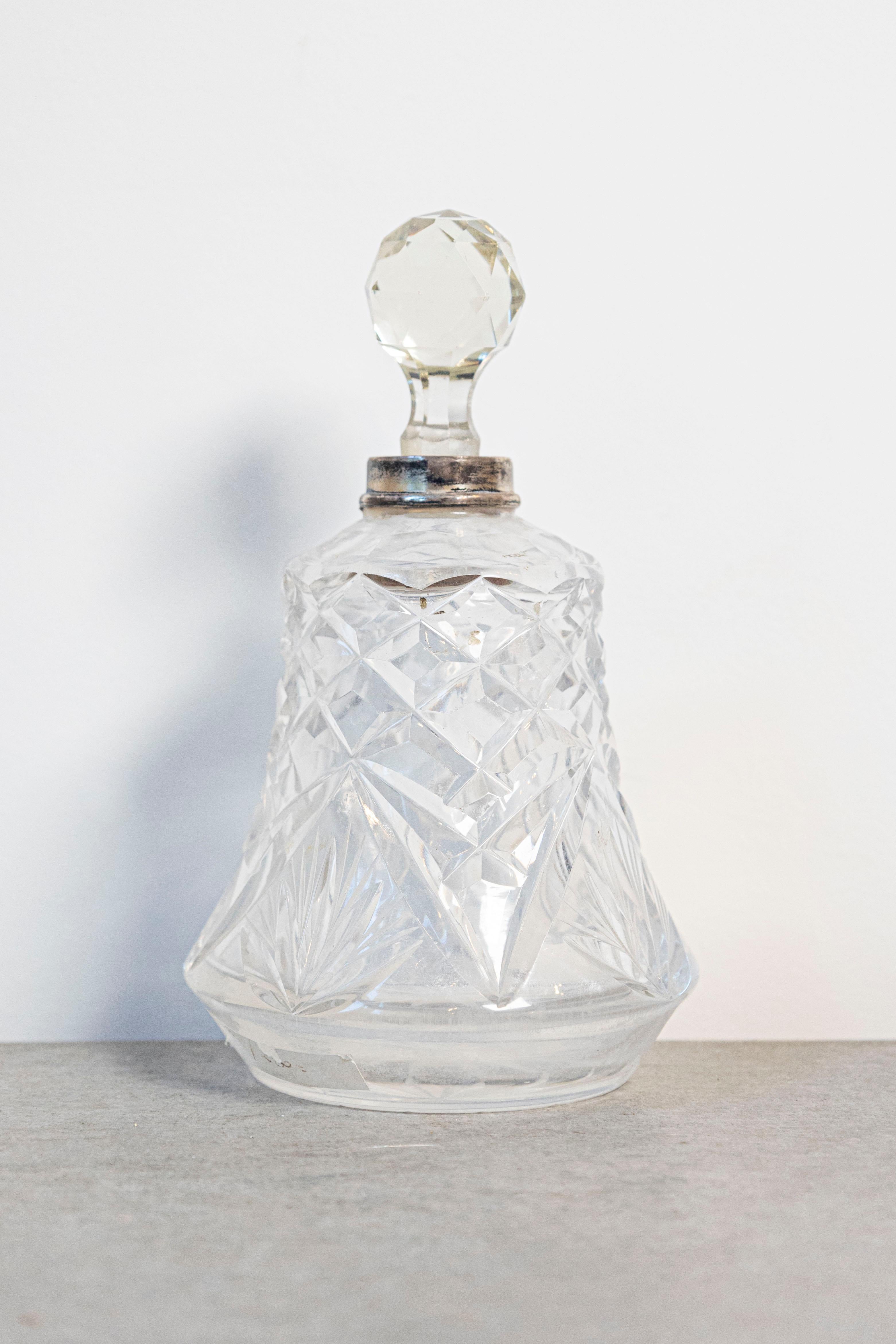 Una piccola bottiglia da toilette in cristallo francese degli inizi del XX secolo, con collo in argento e tappo sfaccettato. Nato in Francia durante i ruggenti anni '20, questo piccolo flacone da toilette presenta un corpo svasato ornato da motivi a