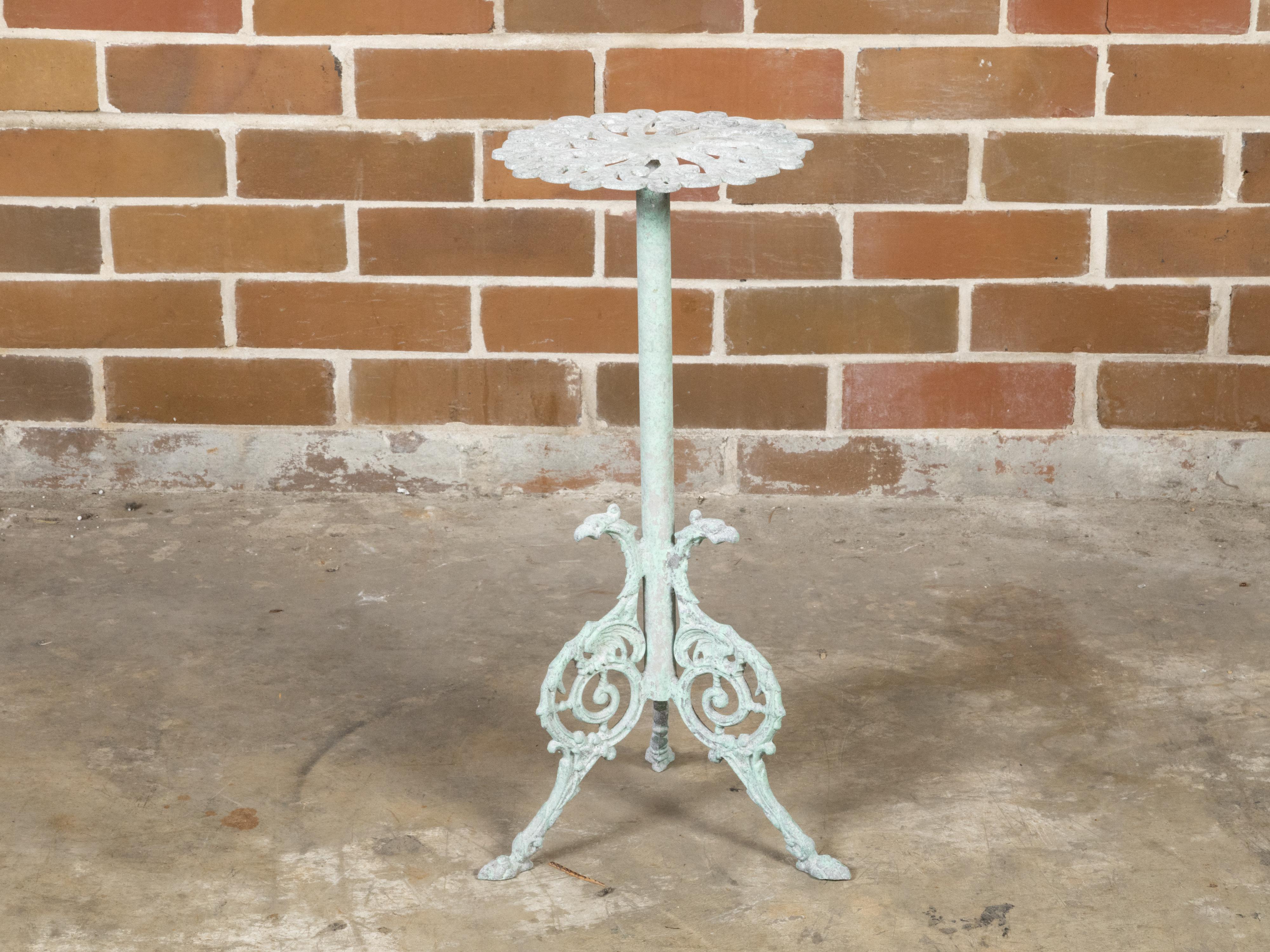 A small French iron garden pedestal side table from the early 20th century, with soft green painted finish, floral inspired top and tripod base on hoof feet. Created in France during the vibrant Roaring Twenties in the first quarter of the 20th