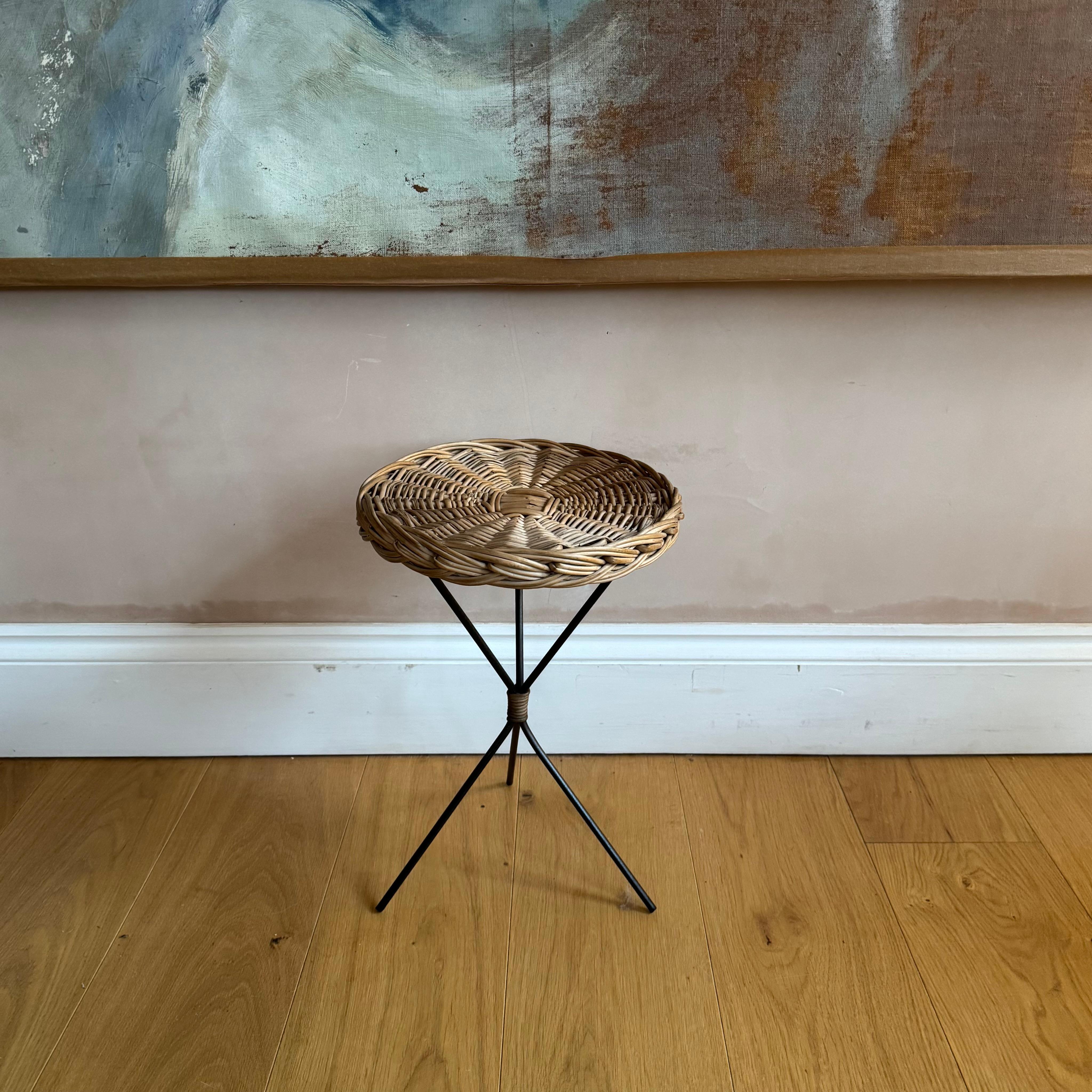 A very sweet small rattan and black metal side table with tripod base. In the style of Raoul Guys. 