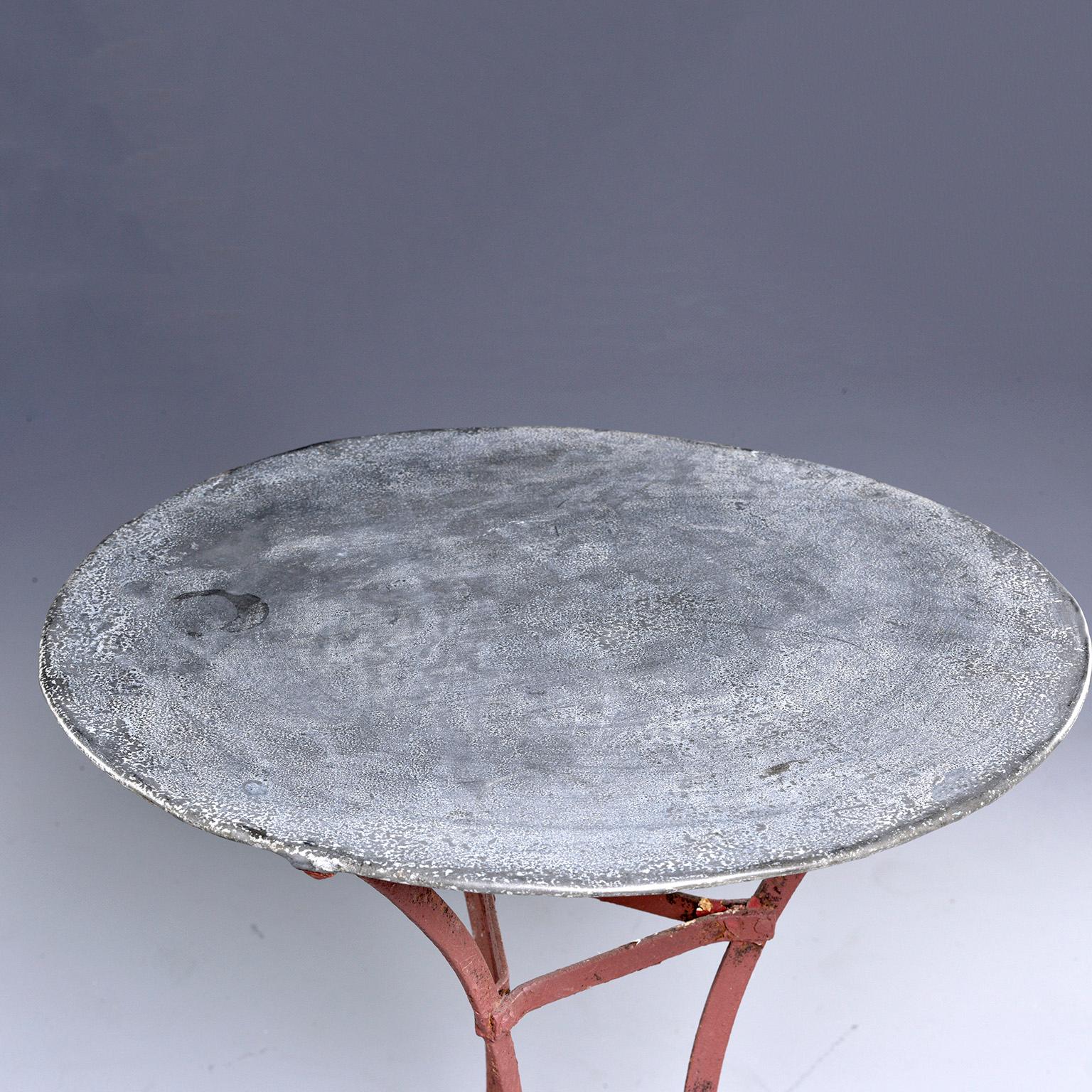 Small French bistro table has a round zinc top with red painted iron base, mid-20th century. Very good vintage condition with original paint and patina, circa 1950s.
  
