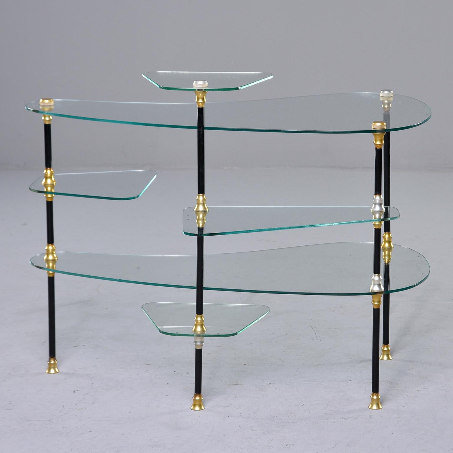 Small French glass etagere or display stand, circa 1950s. Stand features black enameled metal legs with brass plated hardware and six glass shelves of varying size and shape. Great display piece. Maker's name is etched on glass - see photos - but we