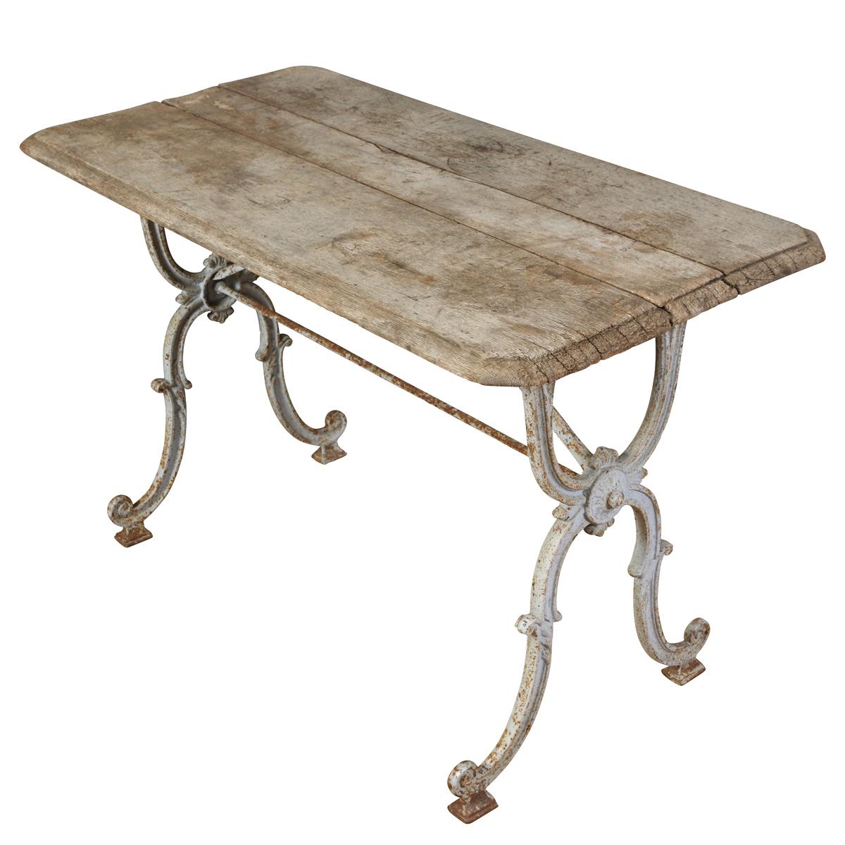 A charming French bistro or garden table featuring an ornate cast iron base with scrolling legs and a naturally weathered wood plank top. Retaining traces of its original white paint and a beautifully aged patina, this piece captures the Belle