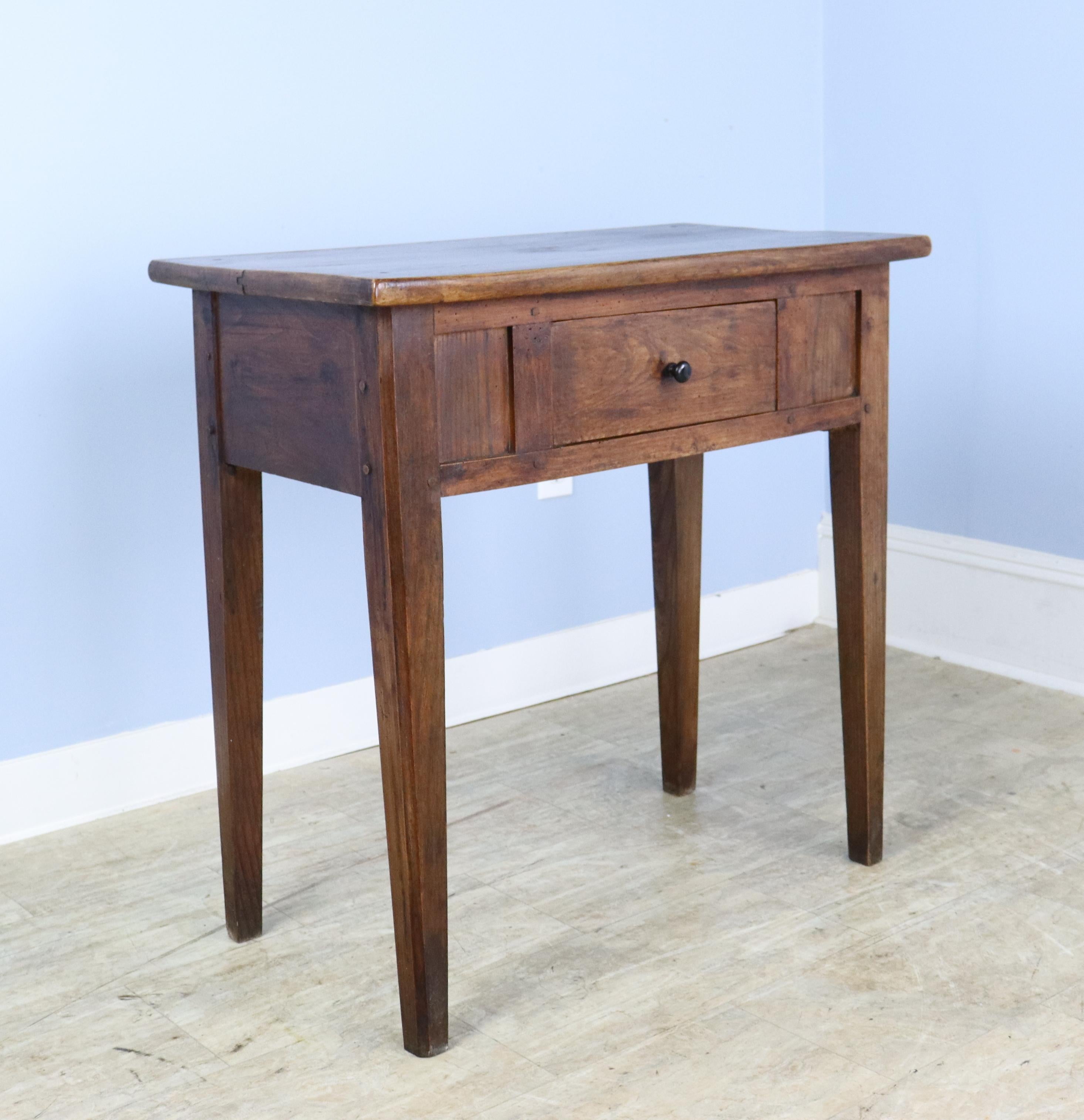 A small serving or side table, with stylish wood detail on the front and a roomy center drawer. This piece is the right size and height to use as a hall table, in a vestibule, or in a smaller dining or living room. The elm has very nice color, grain