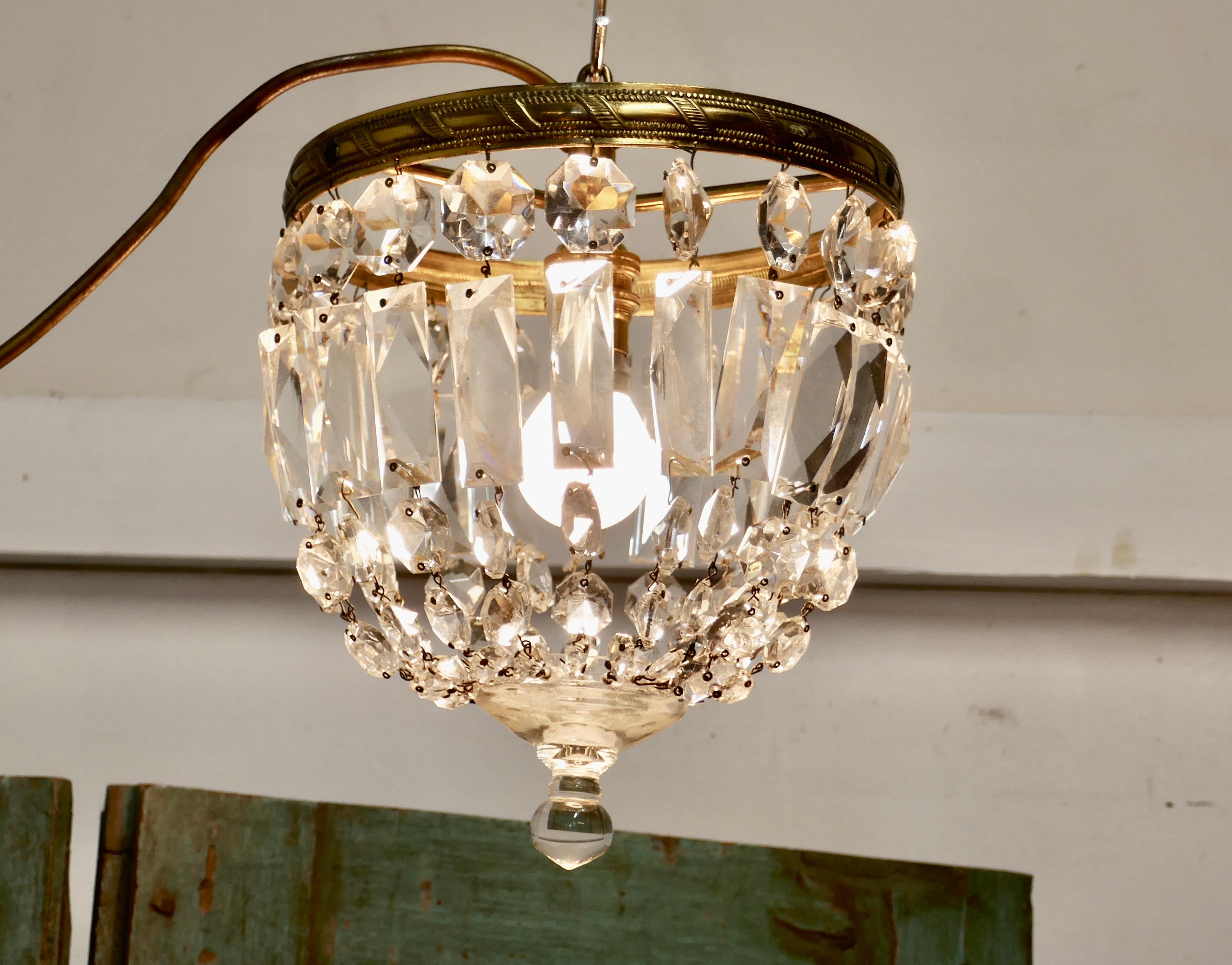 Small French Empire style crystal basket chandelier

This is a lovely piece especially where a very large chandelier is not possible, it has an aged brass frame hung with chains forming a basket and a crystal roundel forming the base
The