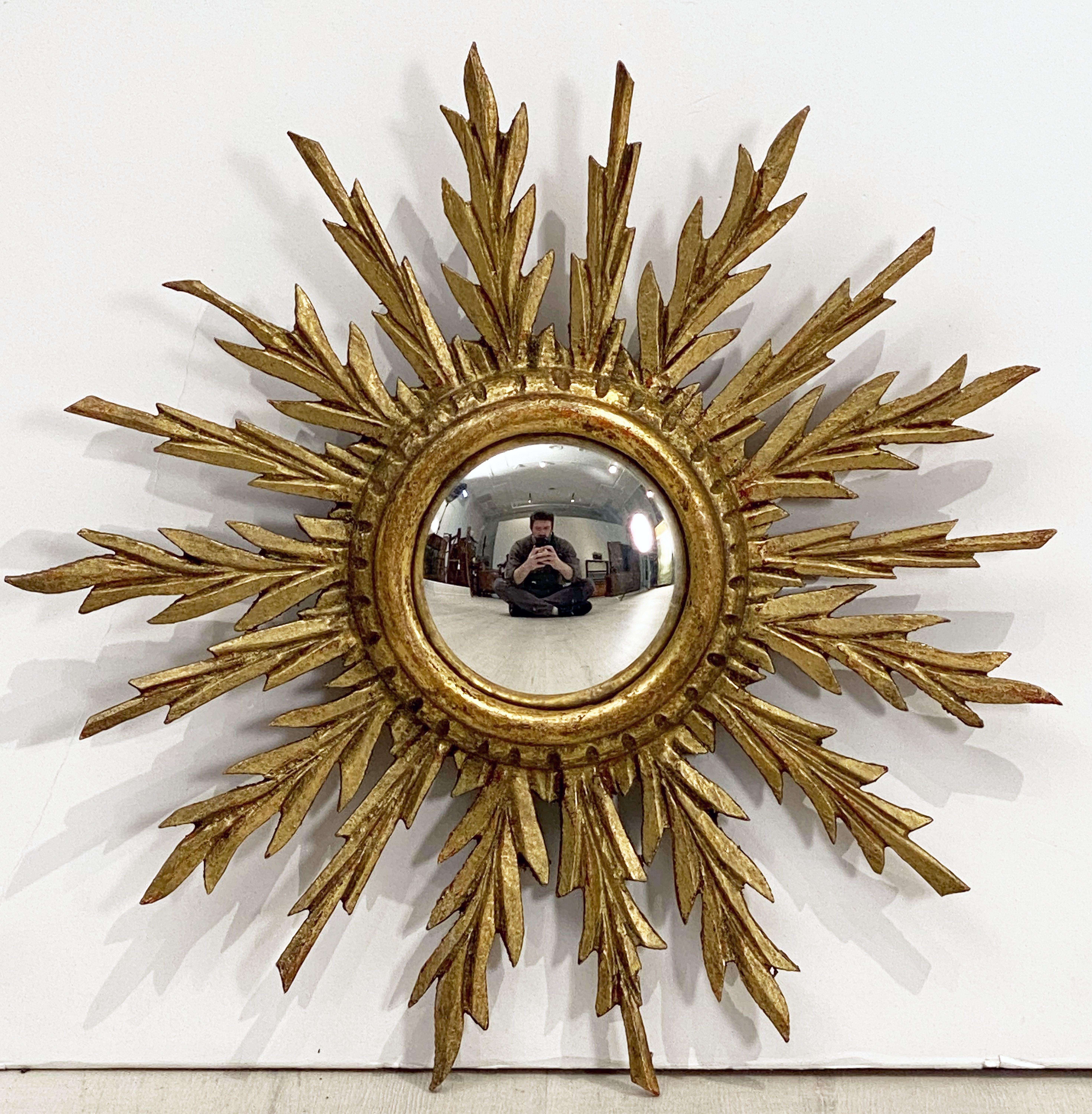 A lovely French gilt sunburst (or starburst) mirror with round convex mirrored glass center in moulded giltwood frame, the bright shining rays in the form of gilded leaves.

Measures: Diameter of 13 inches