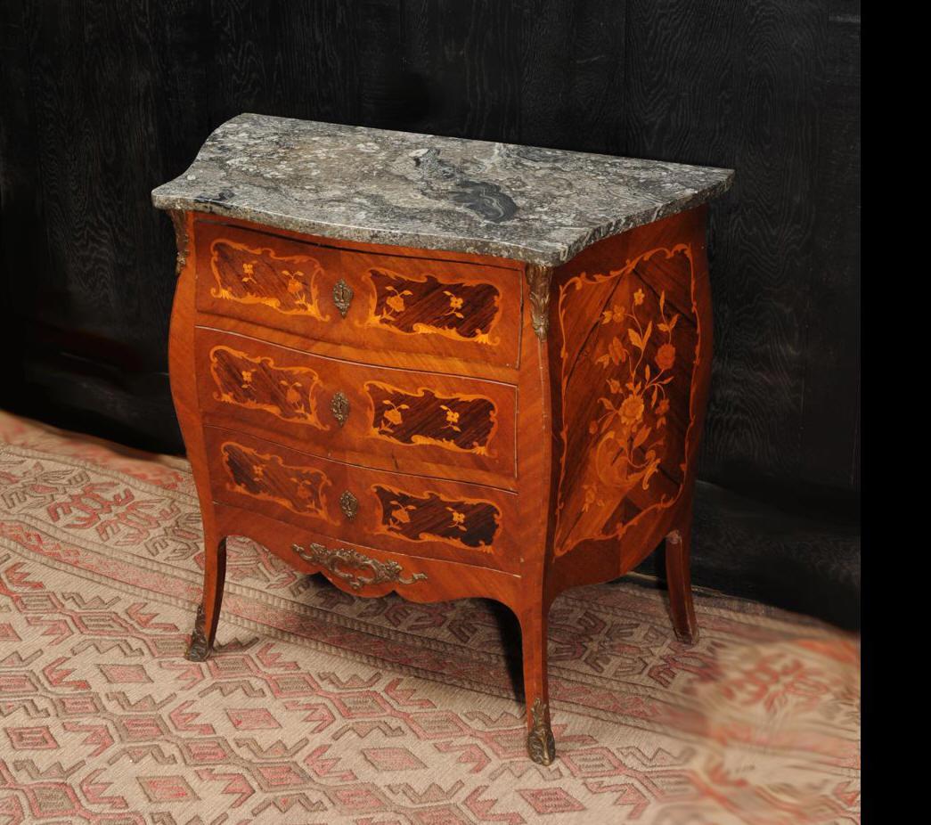 A stunning vintage French Bombe chest of drawers of small proportions. Beautiful Satin wood with marquetry inlay of rosewood and other exotic timbers. The top is a most gorgeous fossil limestone.

Condition is very good with a few small nicks and