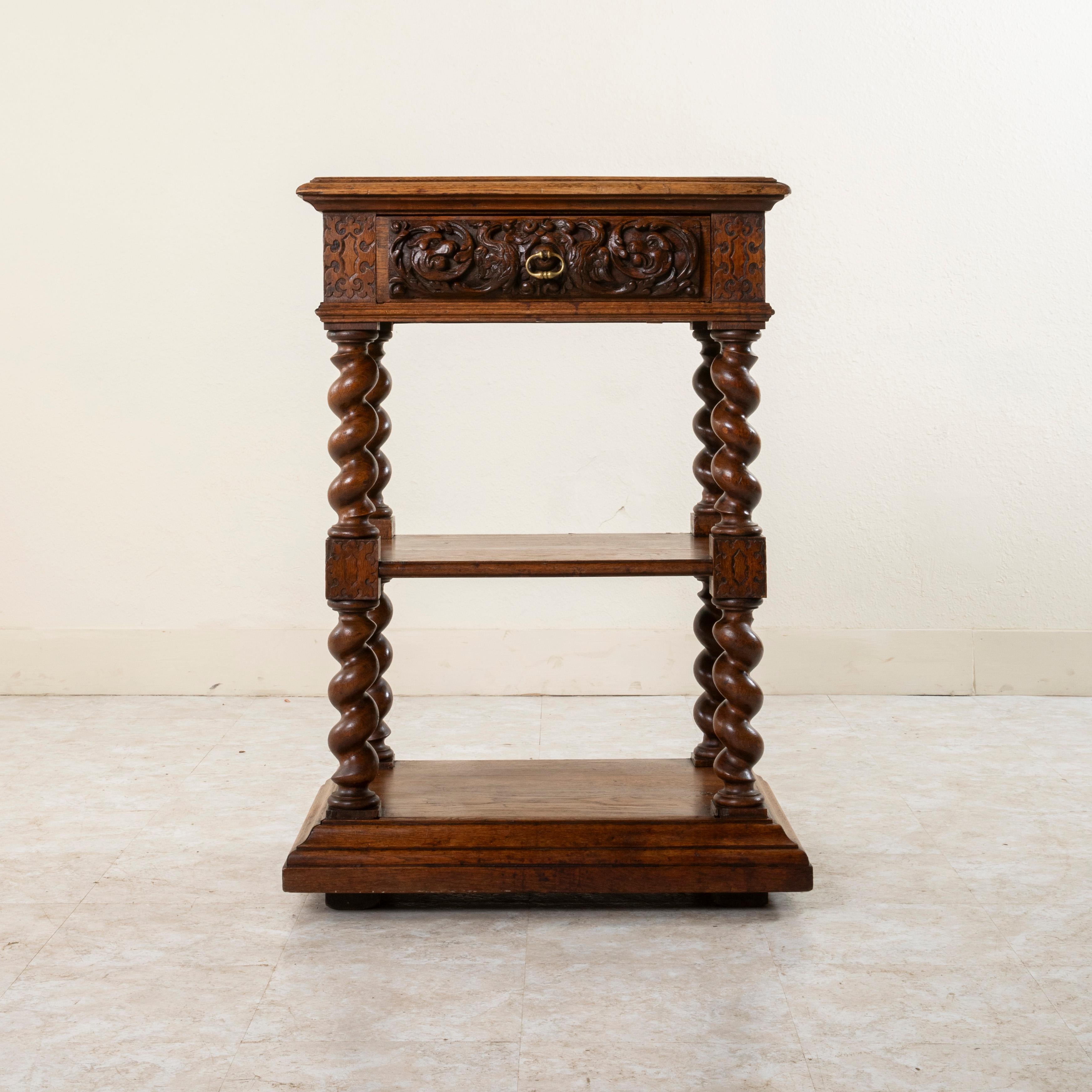 This small scale Louis XIII style hand-carved oak dessert buffet from the late nineteenth century features carvings on three sides. Cartouches and scrolling in bas relief carving adorn the die joints. The drawer front below the beveled top is