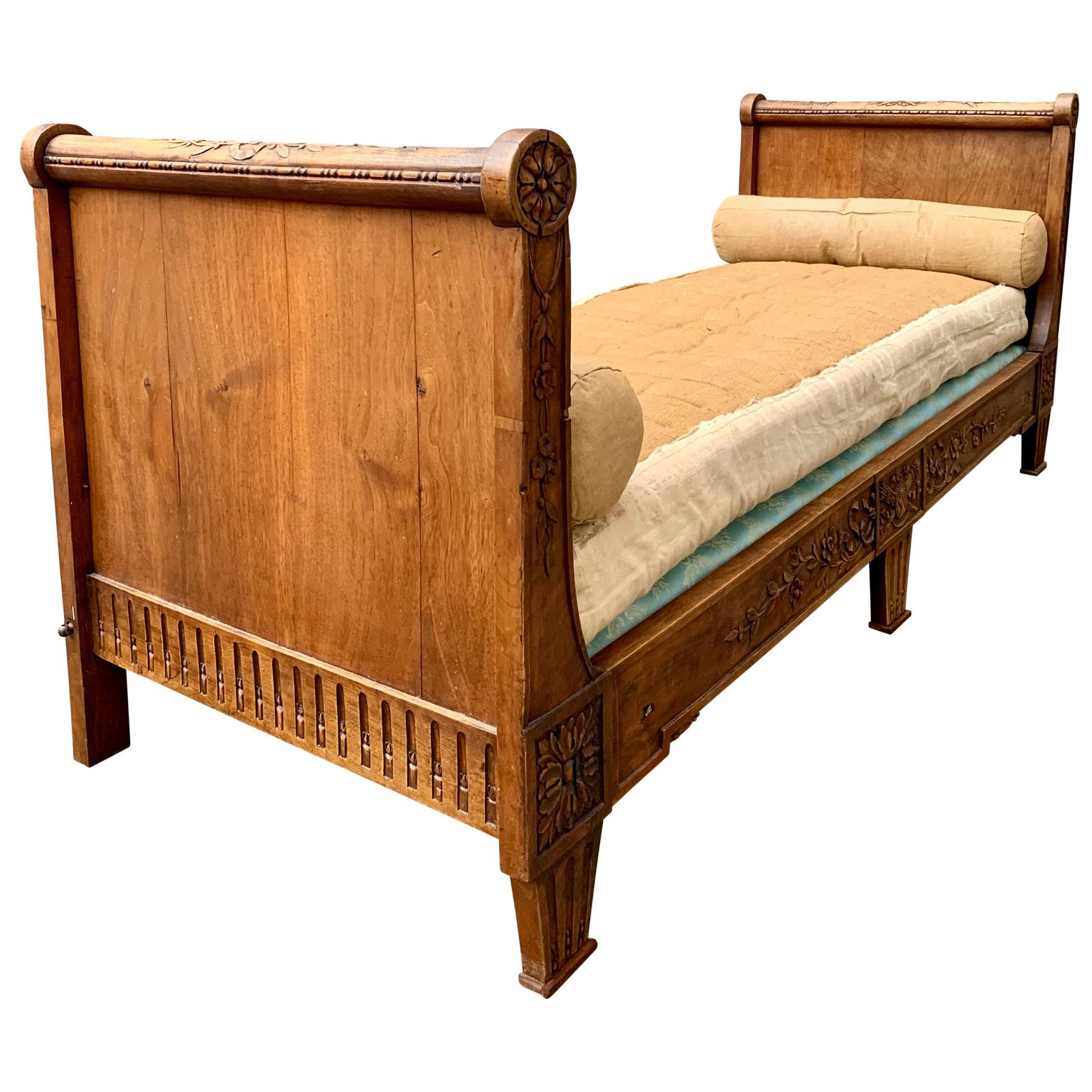 A Louis XVI bed from the turn of the century 17/1800 in carved massive mahogany. 
It features hand carved decorations of flower and a female head in a medallion with arrows and torch. The last 2 symbols represent courage/looking forward and love