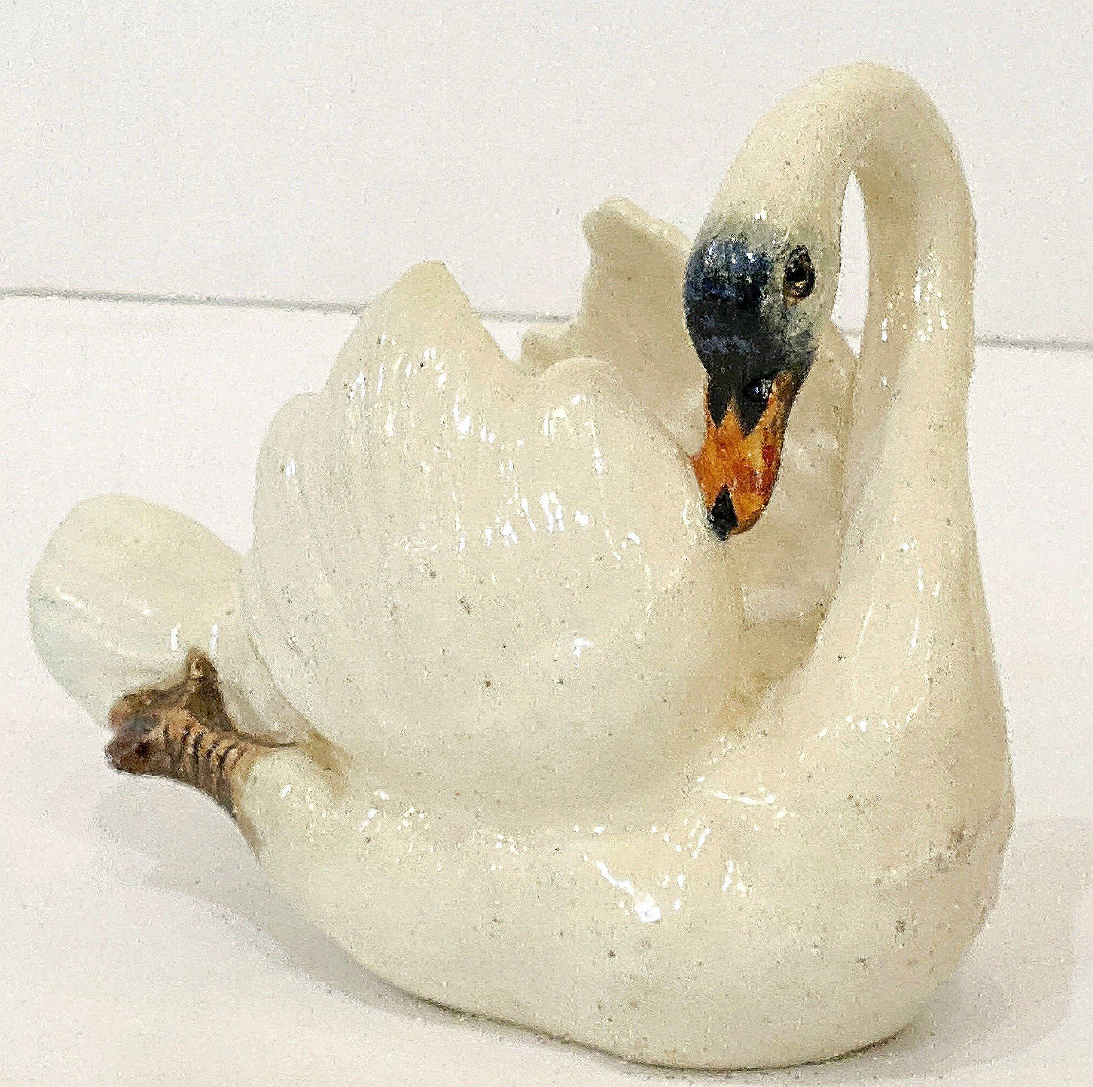 Una raffinata scultura di cigno in ceramica smaltata francese di Majolica barbotine della celebre ditta di ceramiche di Vallauris, Massier, con un cigno elegantemente modellato in bianco con accenti dipinti a mano.

Firmato alla base: Delphin