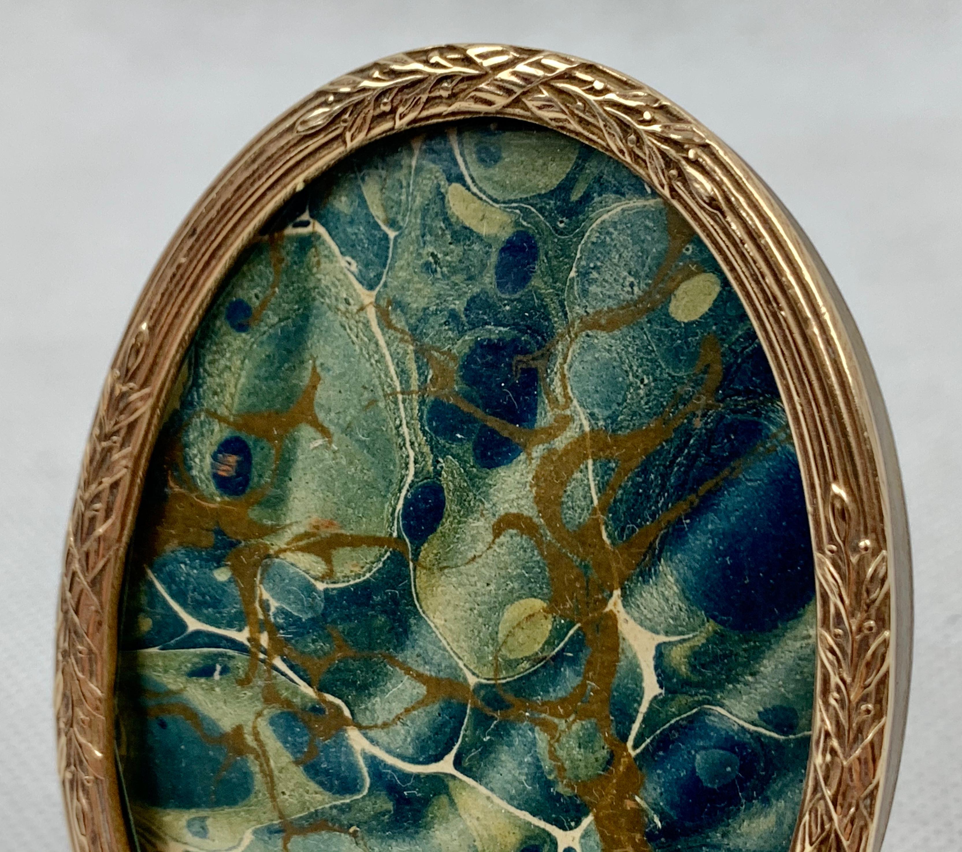 Small French oval Louis XVI gilt frame with a Classic motif of crossed ribbons over reeds. The frame has a split easel for support on the back.

Outer dimensions: H 2.25