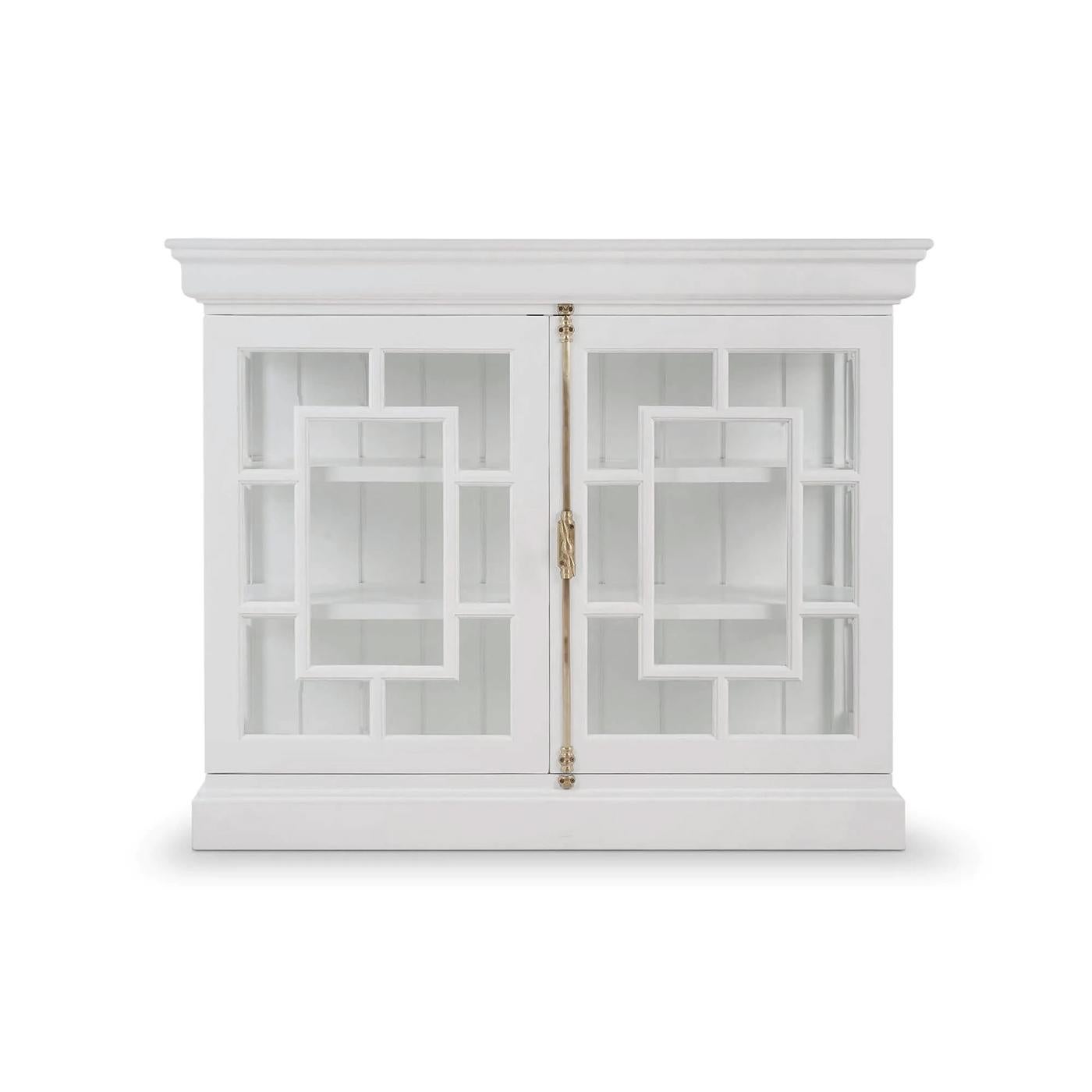 La credenza conferisce una simmetria raffinata e un'eleganza architettonica agli interni contemporanei. Incorniciate da una vera e propria finitura verniciata bianca, le sue ante con pannelli di vetro presentano un traforo geometrico in un motivo