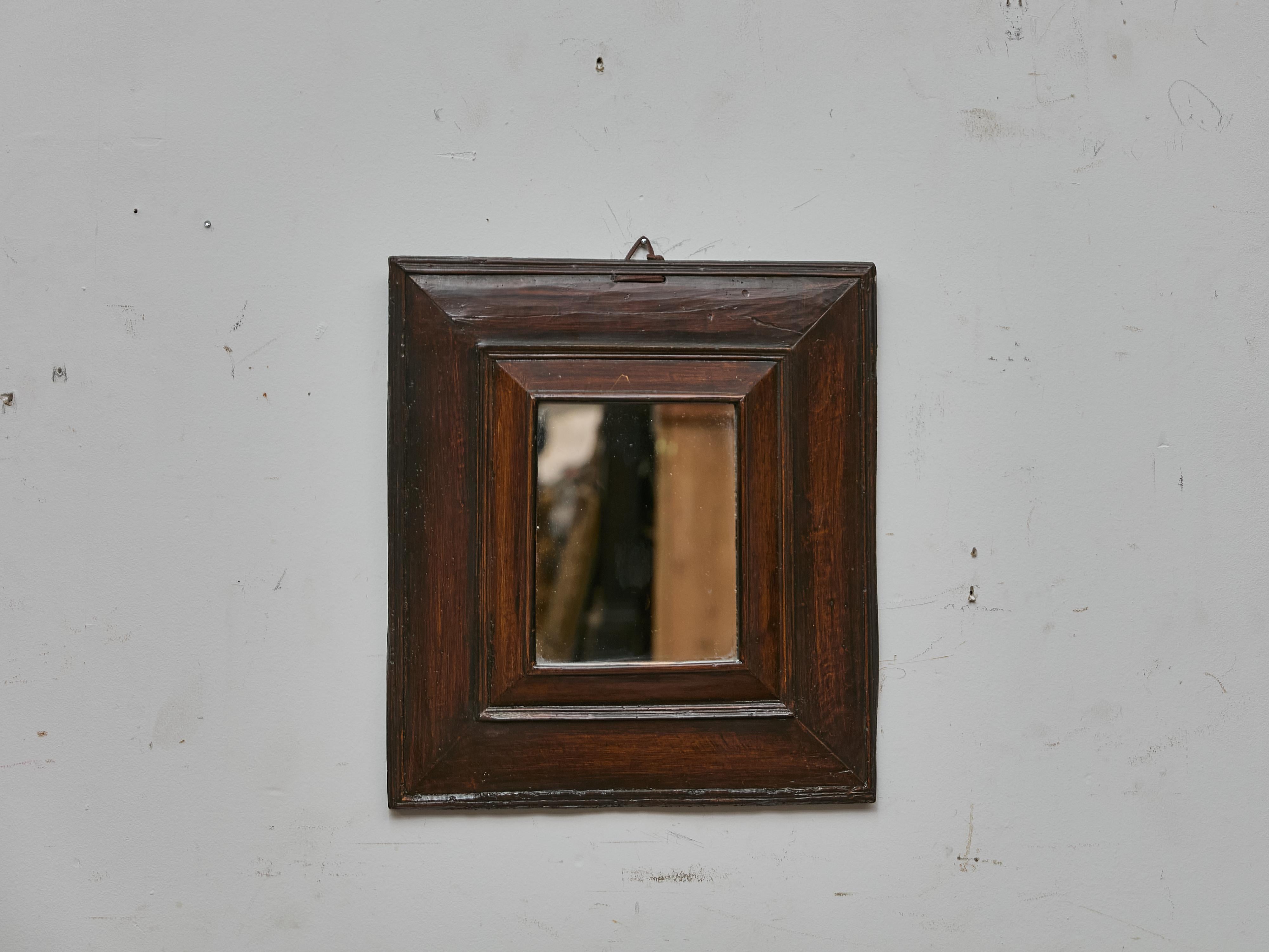 A quietly refined presence, this French mirror dates to the 19th century and features a warm walnut frame with deep moulding and rich patina. The square format gives the piece a sculptural strength, anchored by sharply beveled inner and outer edges