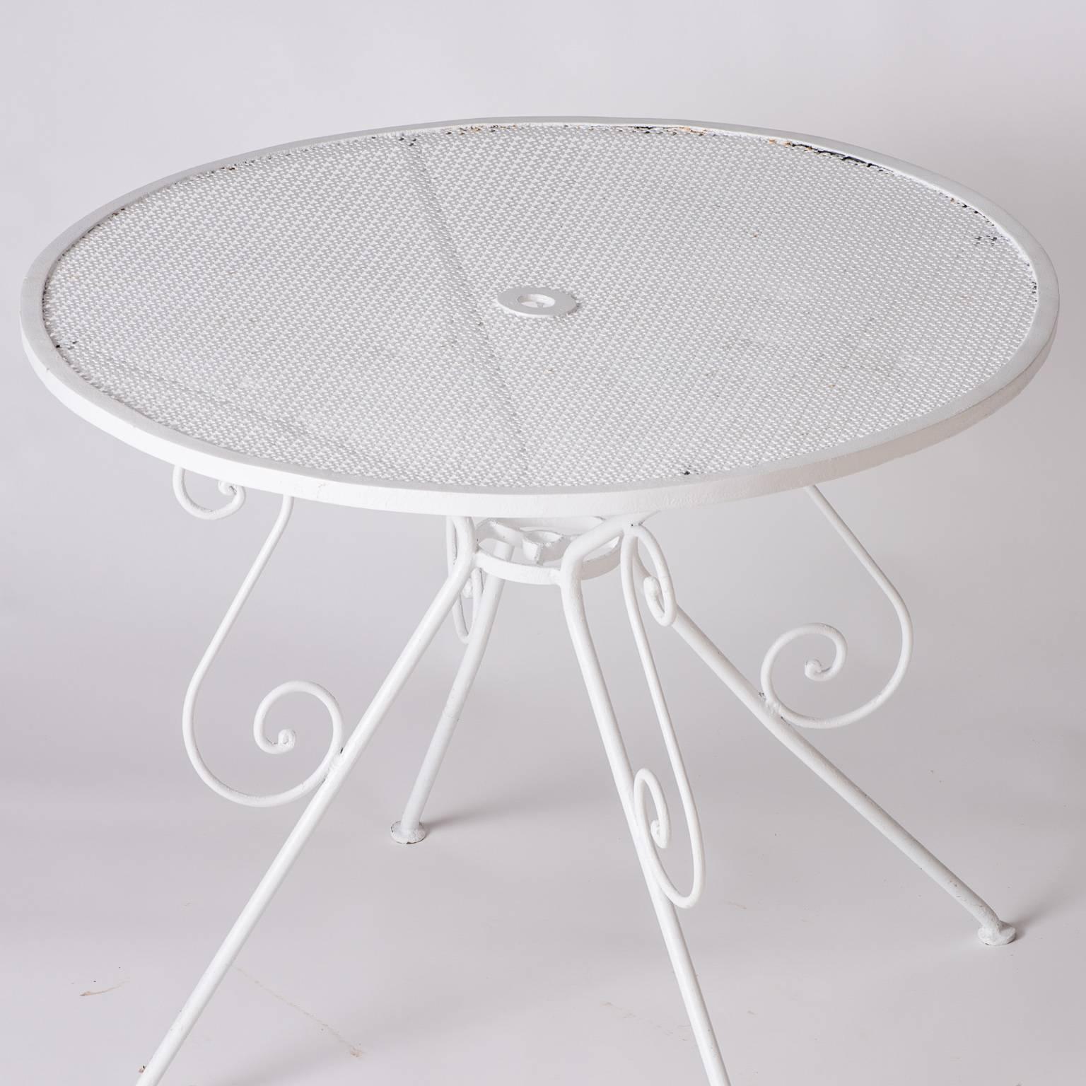 A French wrought iron garden table with a pierced top and an umbrella hole in the center, circa 1950. It is in great condition and has been recently painted with weather resistant paint.

Measures: 29” high
35” diameter.