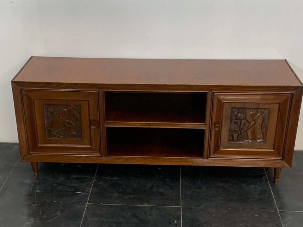 Servant of great quality solid walnut, has 2 side doors with carved panels with characters of Futurist taste with gouged bottom, the center open compartment divided into 2 compartments, all resting on conical feet with brass tips. The lines are
