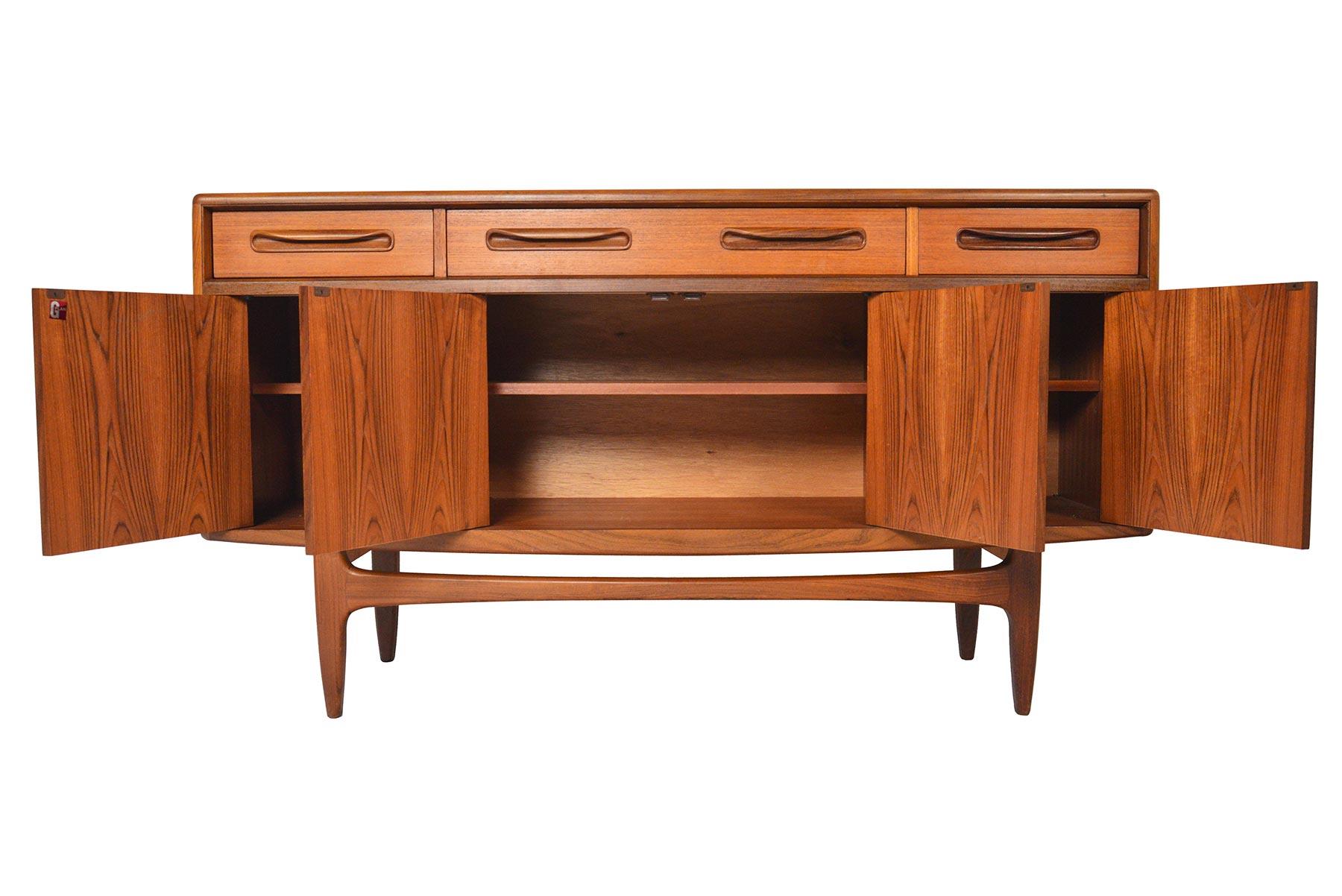 This small Mid-Century Modern G Plan Fresco teak credenza was designed by Victor Wilkins in the 1960s. Beautiful afromosia pulls adorn the drawers and doors of this piece. Left, center, and right doors open to reveal open storage and adjustable