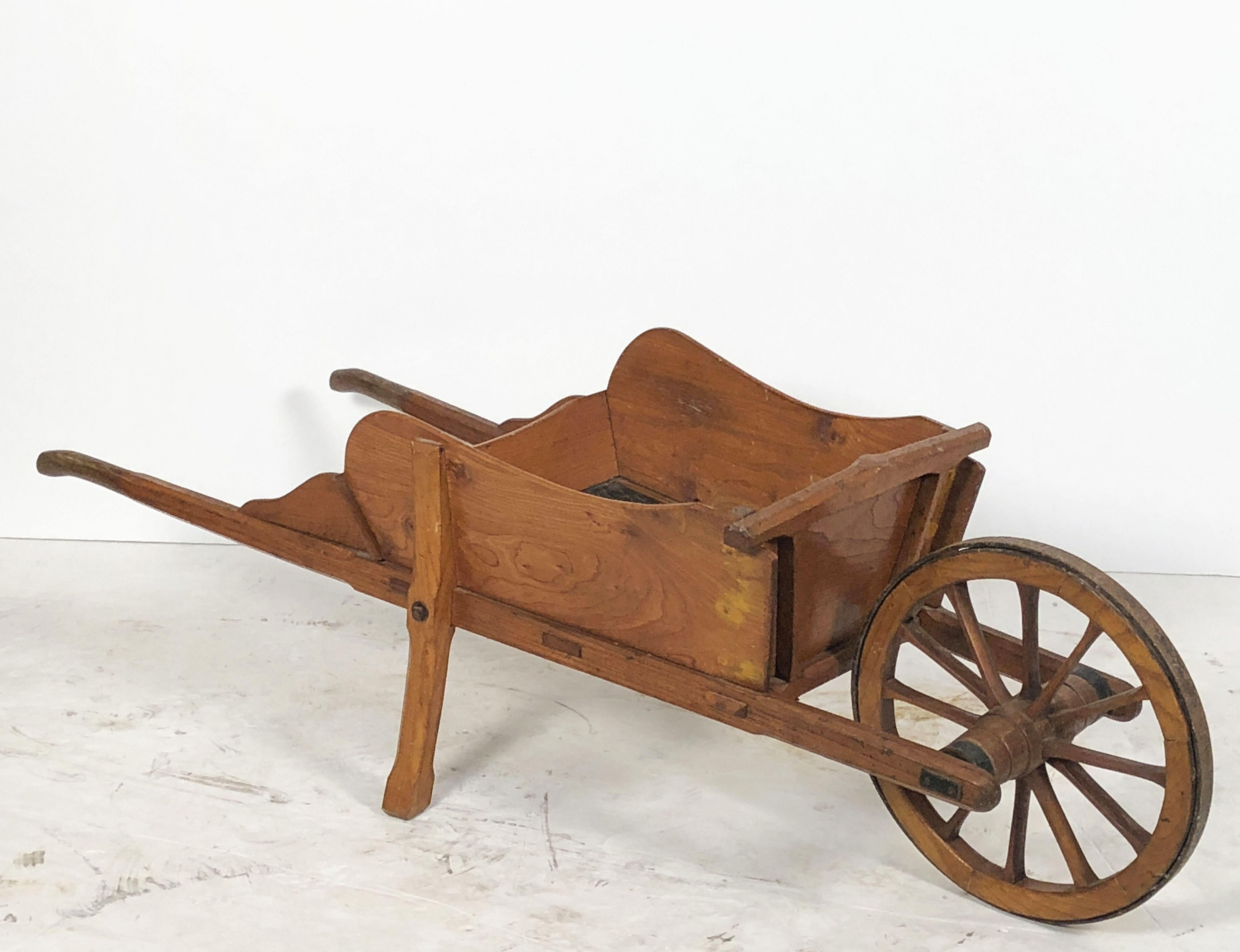 A small gardener's wheelbarrow from England - of finely-patinated wood with an iron-bound spoked wheel.

Perfect for displaying plants or as a decorative feature in a garden room or patio.