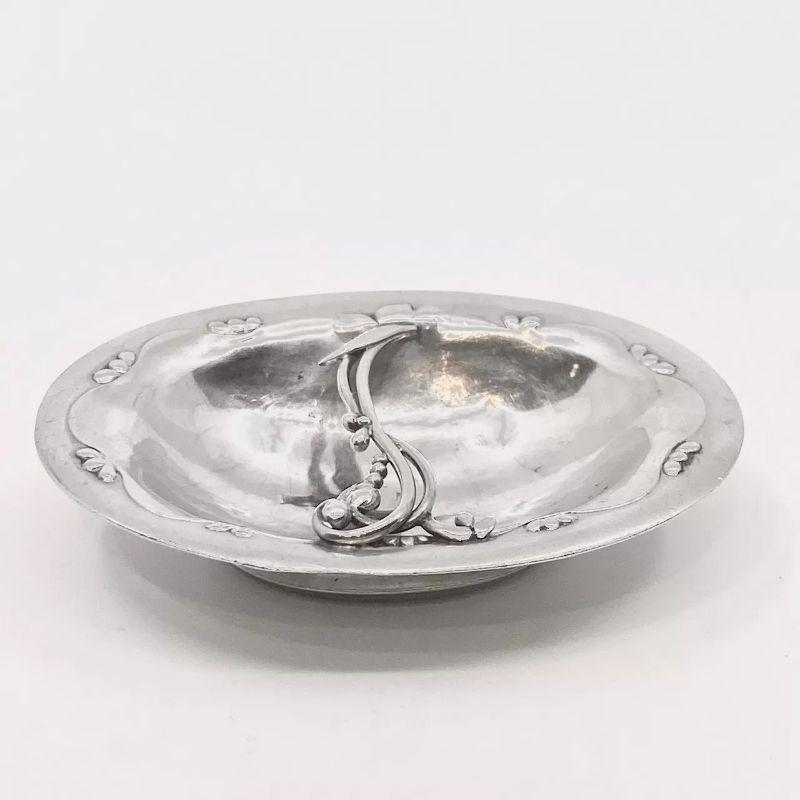 This is a small sterling silver Georg Jensen ashtray, design #243A by Georg Jensen from circa 1918.

Additional information:
Material: Sterling silver
Styles: Art Nouveau
Hallmarks: Marked underneath with Georg Jensen hallmark “A 925 STERLING