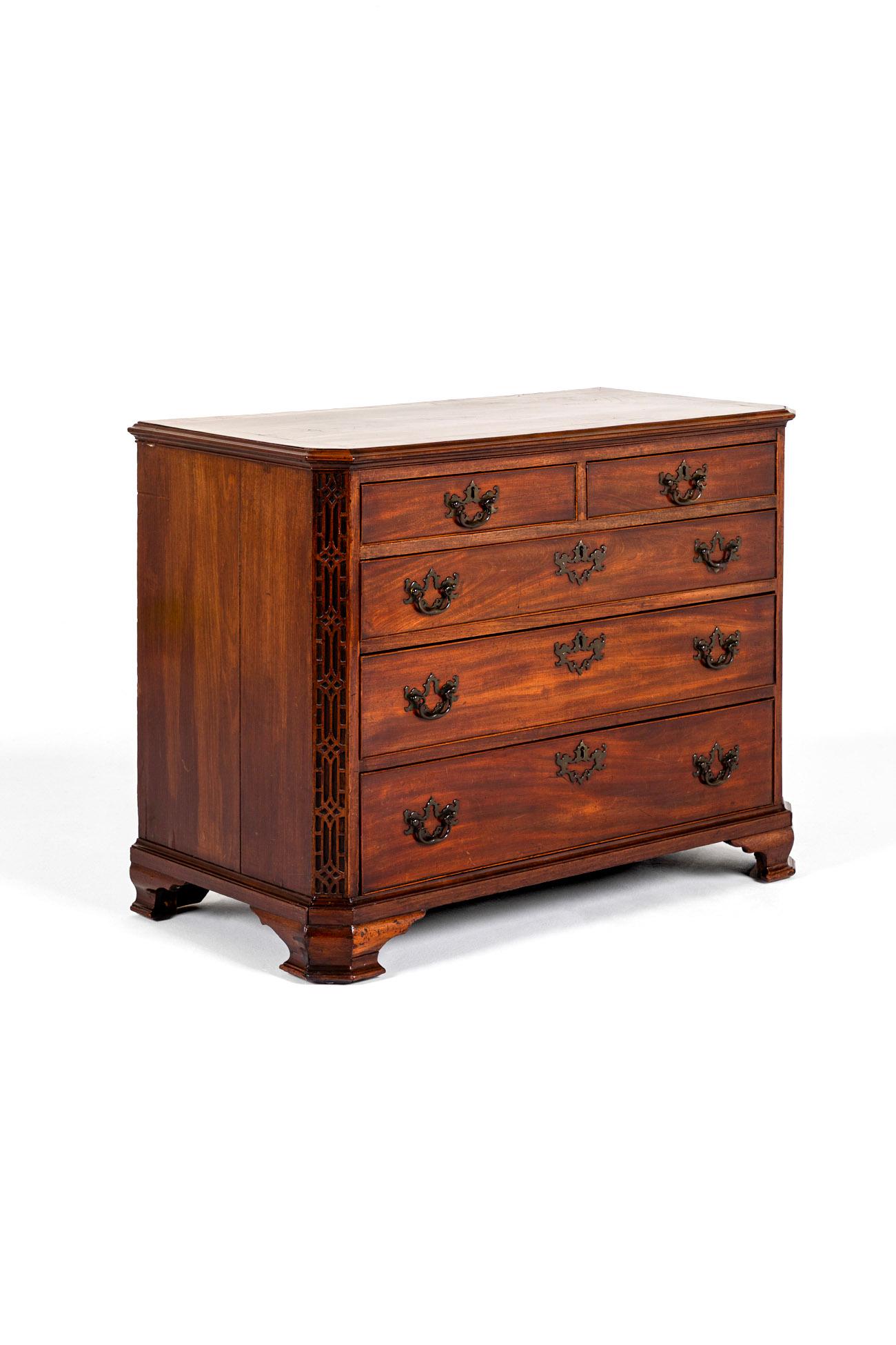 A fine well proportioned George III mahogany chest with a crossbanded top over two short and three graduating drawers.

The drawers are flanked by beautiful canted blind fretwork fore angles. The drawers are complemented with the original  brass