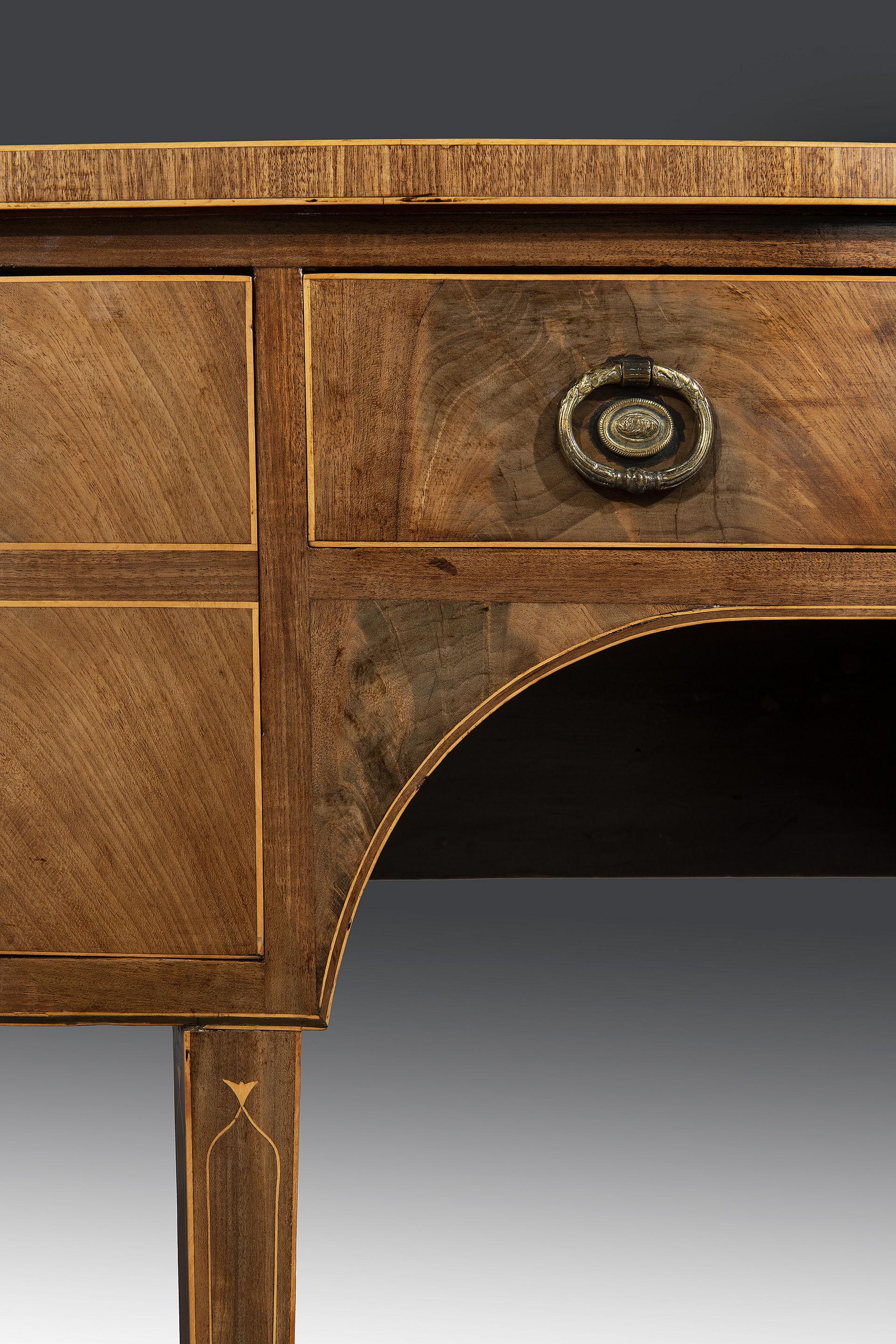 The mahogany top has a faded golden color that retains a lively grain to the veneer above a cross-banded boxwood strung edge. The flamed mahogany drawers are book-matched and strung in boxwood with satinwood escutcheons and fitted with later