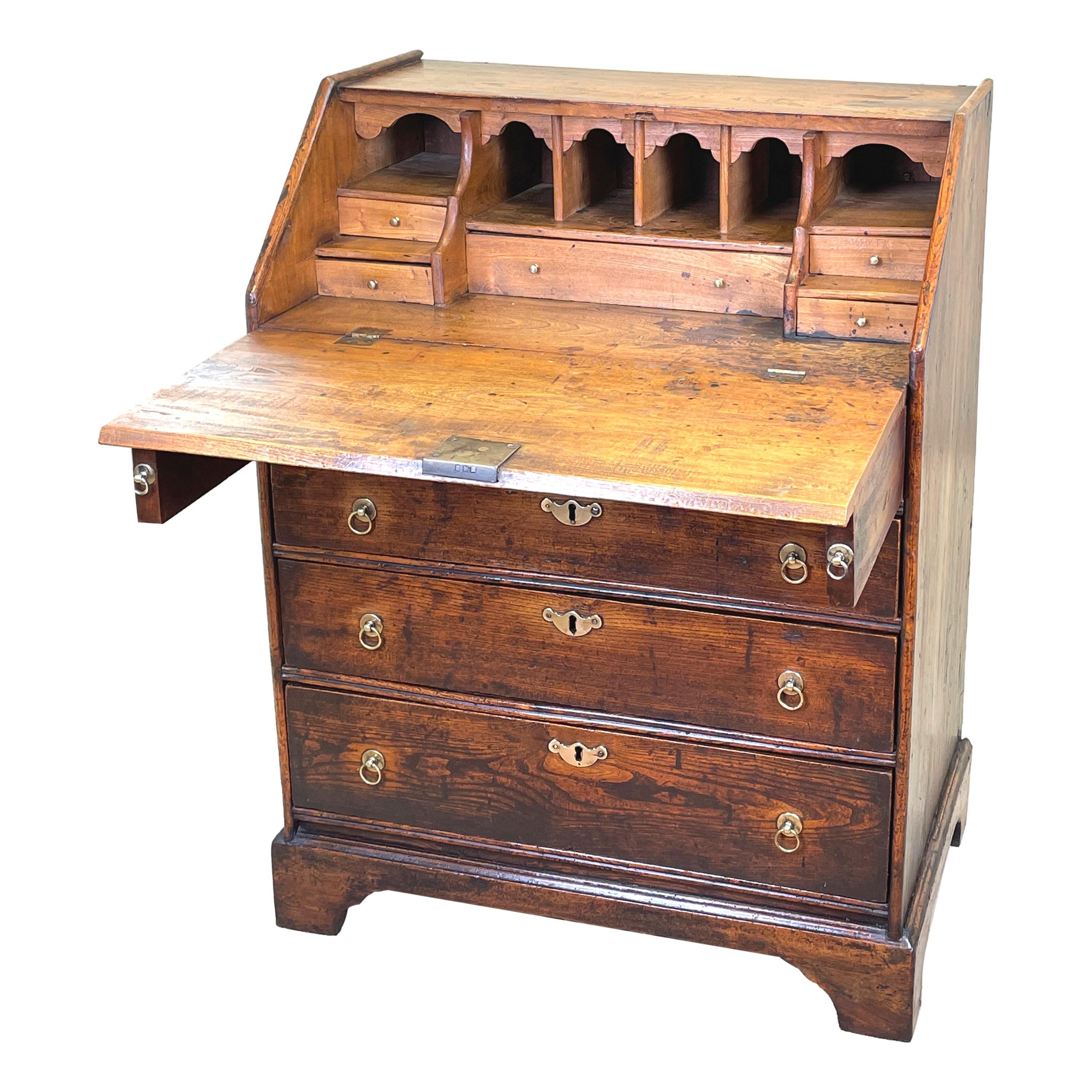 A delightful early 18th century George I Period Elm 
bureau of diminutive proportions having well figured
fall front enclosing drawers and pigeon holes over
two short and three long drawers with original
brasswear raised on original shaped