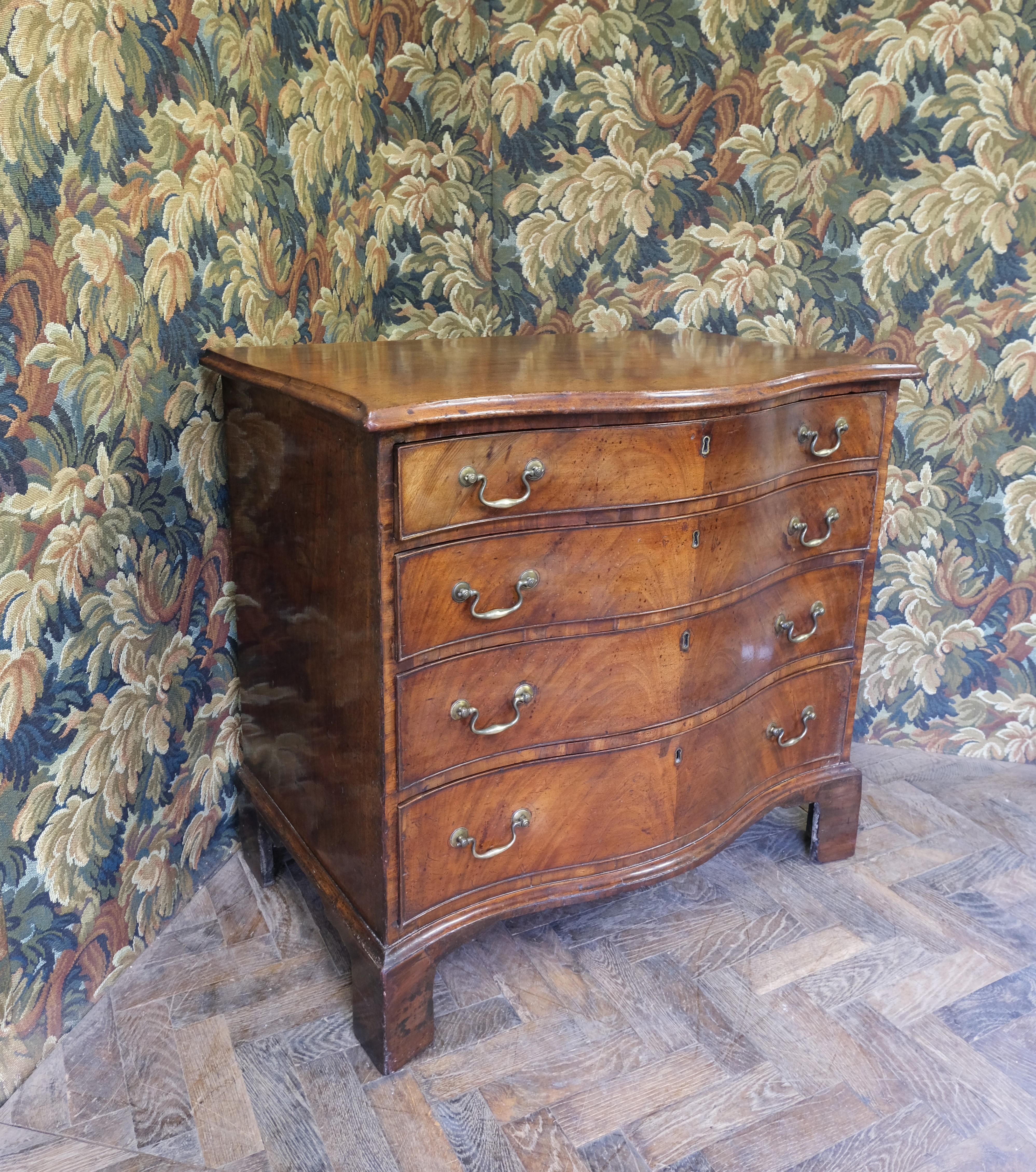 Hutton-Clarke Antiques proudly offers a stunning Georgian Serpentine chest of drawers, a masterpiece of the Georgian era. This piece features a striking serpentine front with book-matched mahogany flame veneers, elegantly standing on original