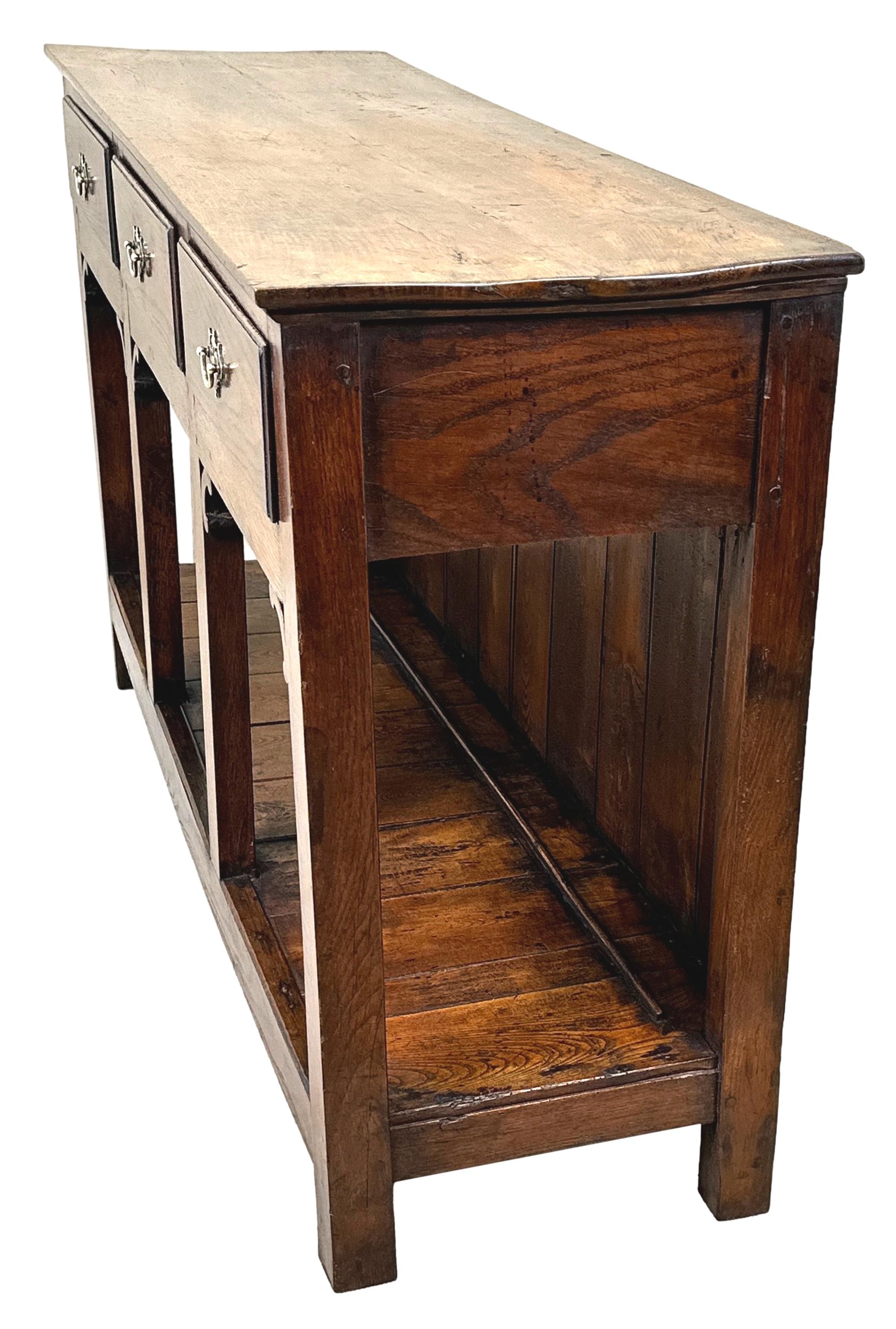 A Very Attractive 18th Century, George III Period Oak Dresser Base, Of Unusual Small Proportions, Having Well Figured Rectangular Top Over Three Frieze Drawers, With Replacement Brass Plate Handles, Raised On Elegant Square Upright Supports With