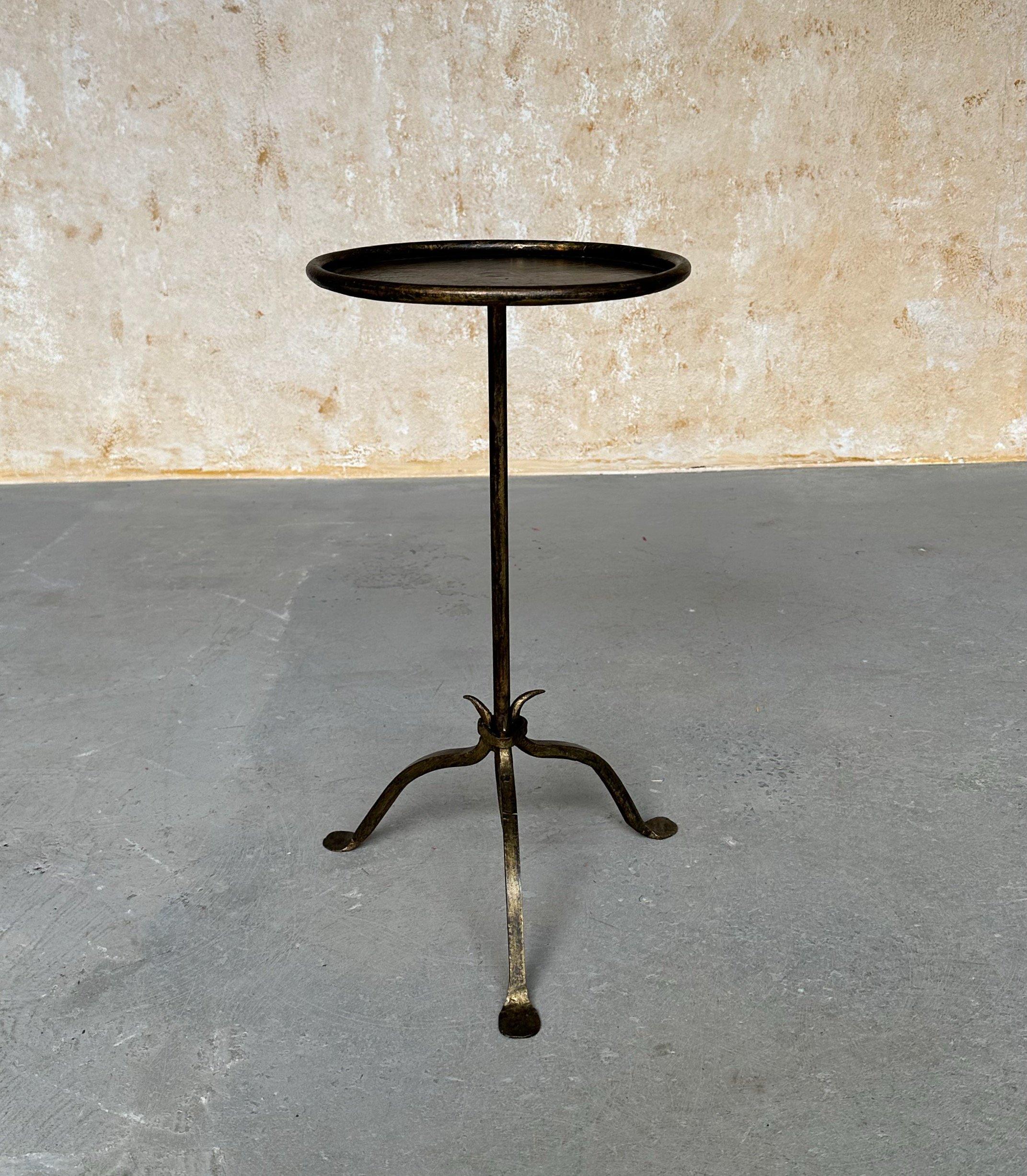 This lovely recently fabricated Spanish iron side table features a distinctive design with a central stem that tapers to a fine point, attached to a tripod base that comprises three subtly curved legs. The round top is encircled by a rolled frame,