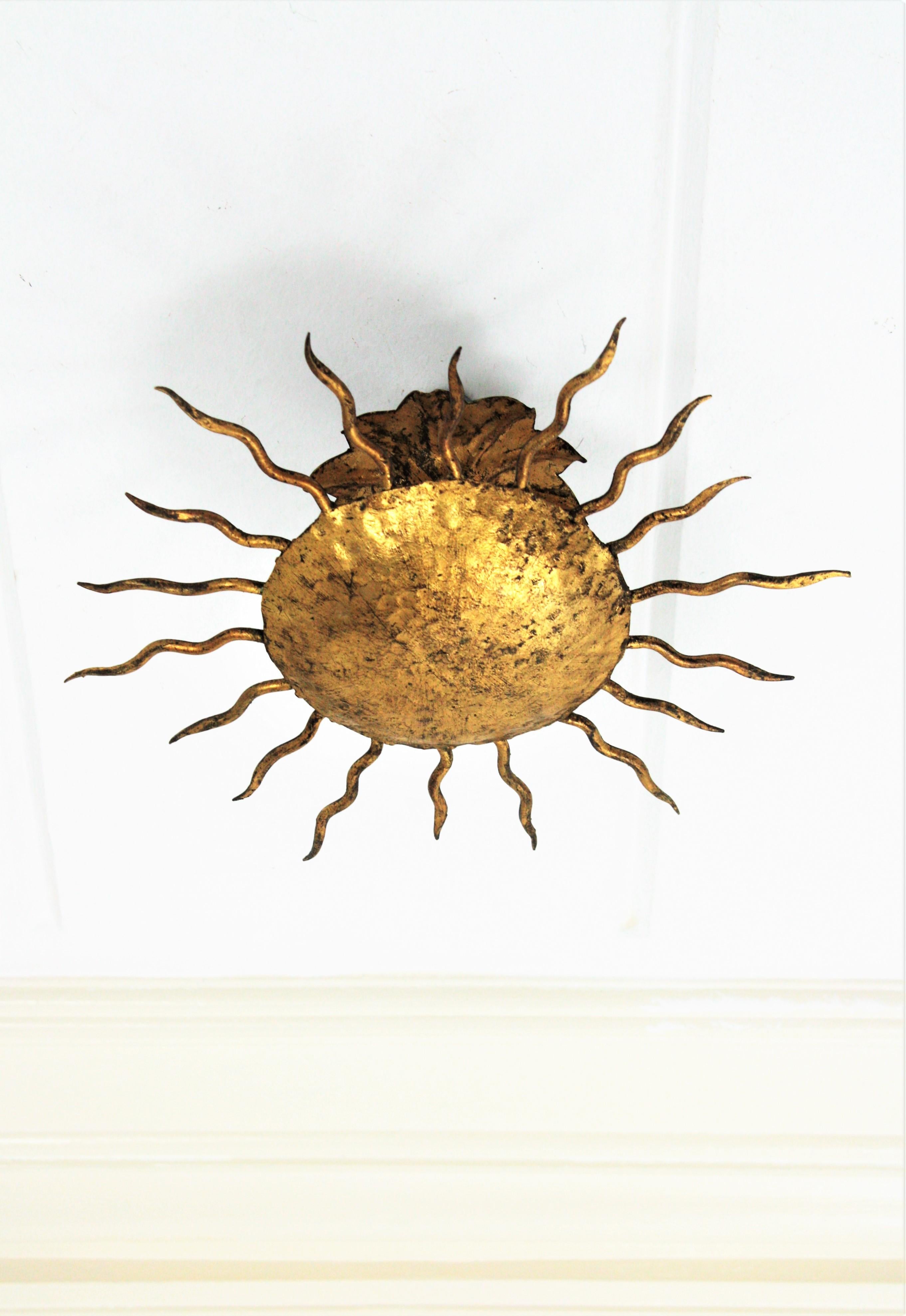 Small Gilt Iron Sunburst Flush Mount Ceiling Light / Wall Sconce. Spain, 1940s
Lovely hand-hammered iron gold leaf gilt sunburst light fixture in an unusual small size. In the style of Gilbert Poillerat
Richly decored in the central part with the