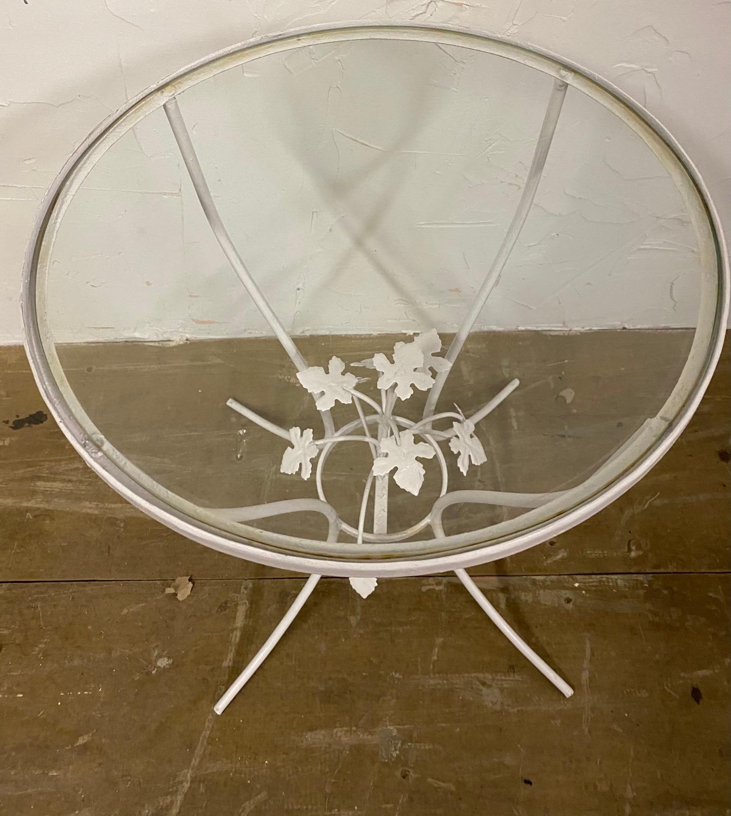 Petite round metal and glass painted Salterini style garden side table with center leaf design.