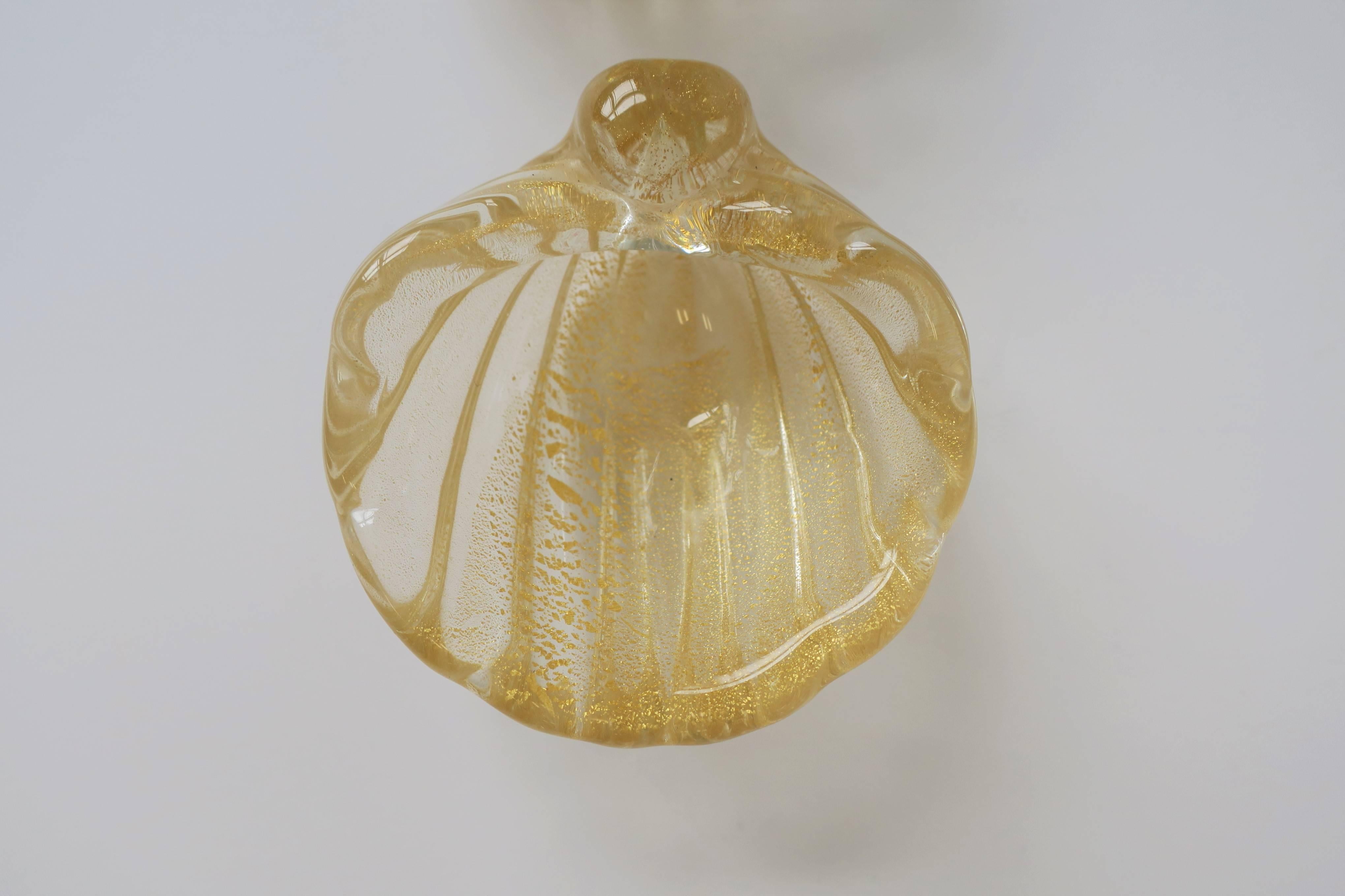 A beautiful small gold and clear hand blown Italian Murano art glass seashell form bowl in the style of Barovier e Toso. This small seashell bowl could be used as decorative piece on a table, desk, or vanity, etc., to hold jewelry or anything small