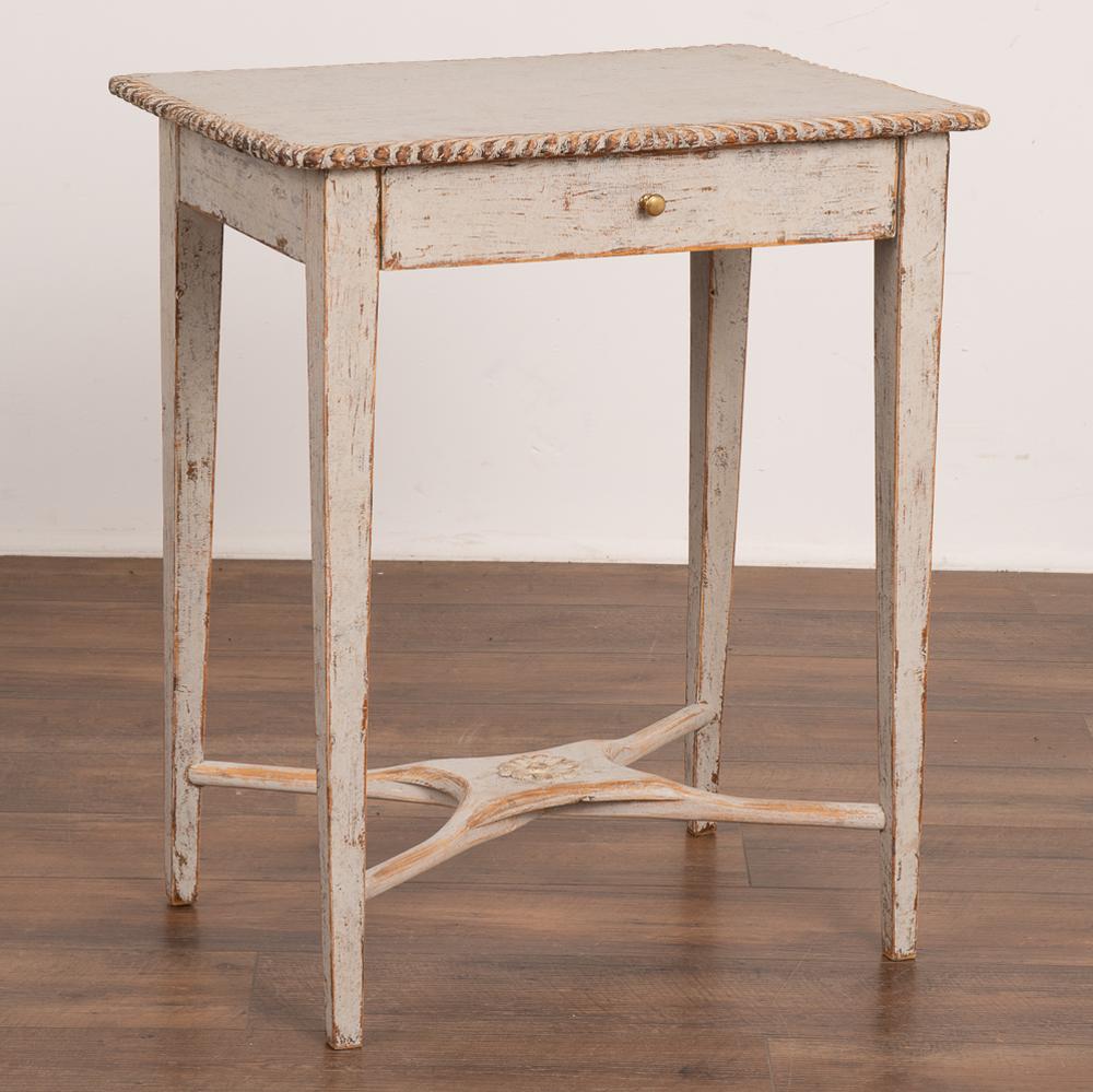This delightful country Gustavian table with decorative carved edges will make a lovely small side table or nightstand.
The table has a newer, professionally applied layered gray painted finish which has been gently distressed matching it's age and