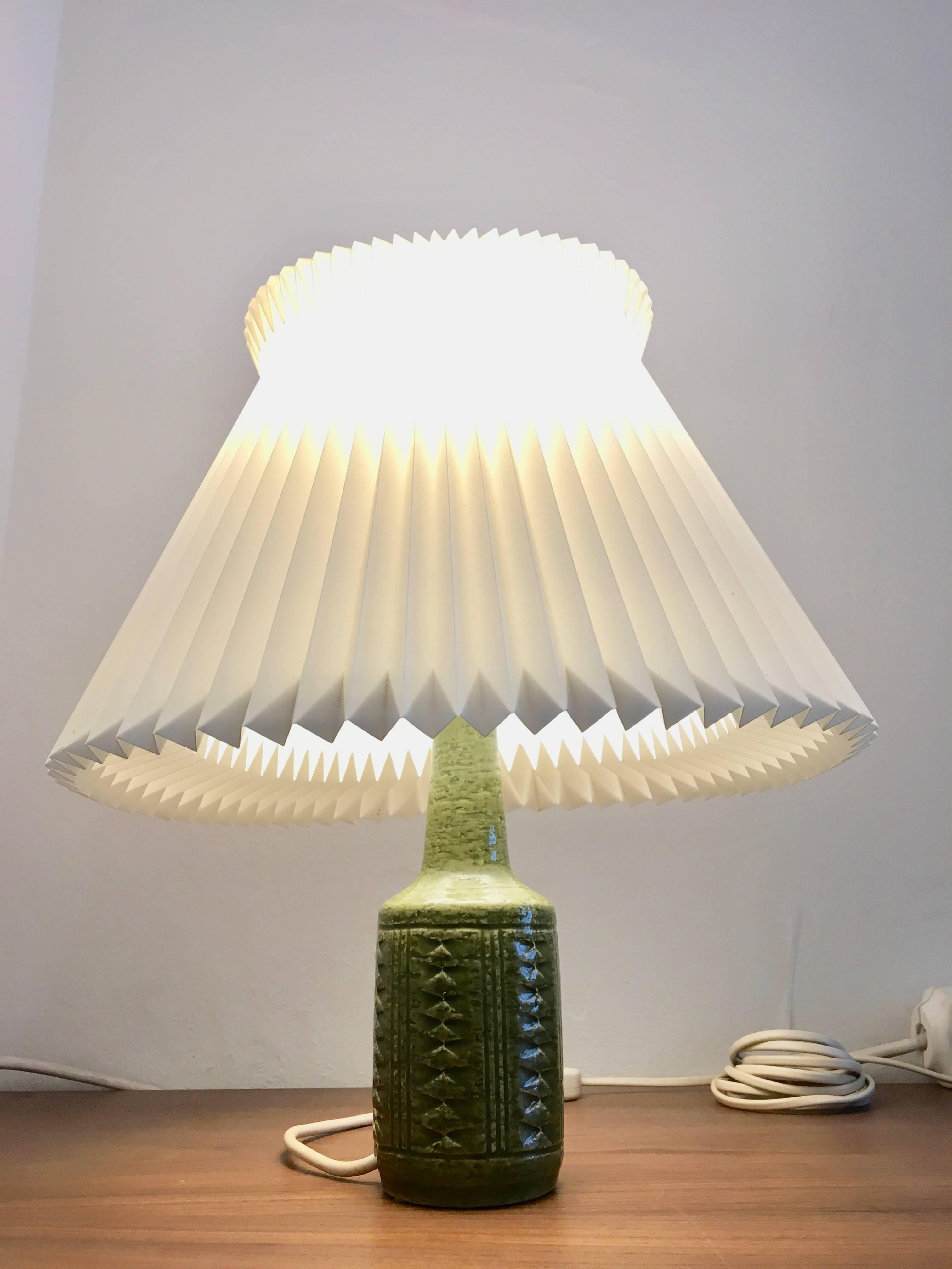 Stylish lamp from Danish Palshus with lovely grass green glaze and a Le Klint shade.
The lamp is made with chamotte clay which gives a rough surface and makes the shiny glaze look even more vivid,
circa 1960s.
Marked on verso: Palshus