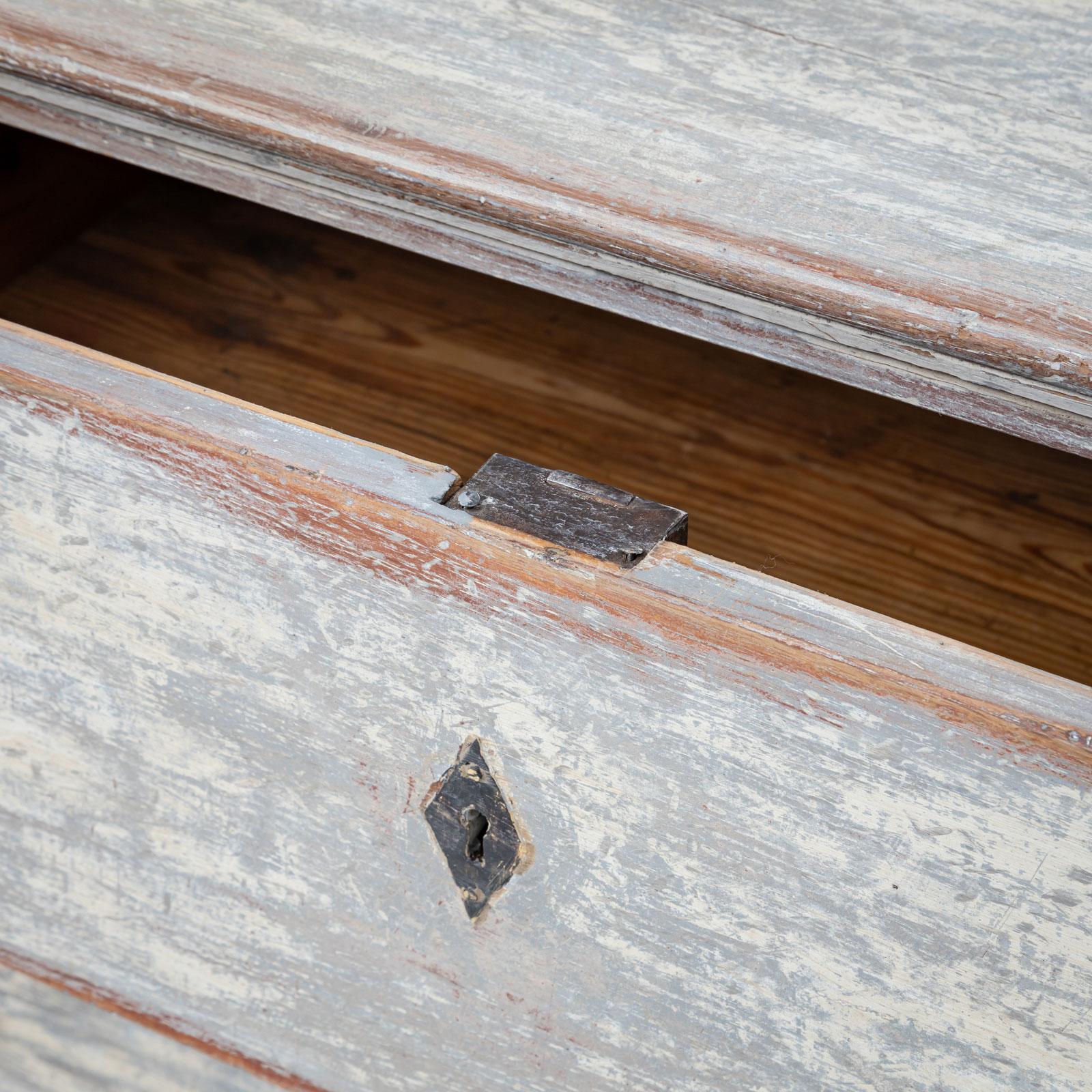 Eleganza della piccola commode Biedermeier che poggia su alte gambe ricurve. Il mobile è dotato di due cassetti con chiavi di sicurezza a forma di diamante. È stato rifinito di recente in grigio e bianco con una patina antica, che aggiunge un tocco