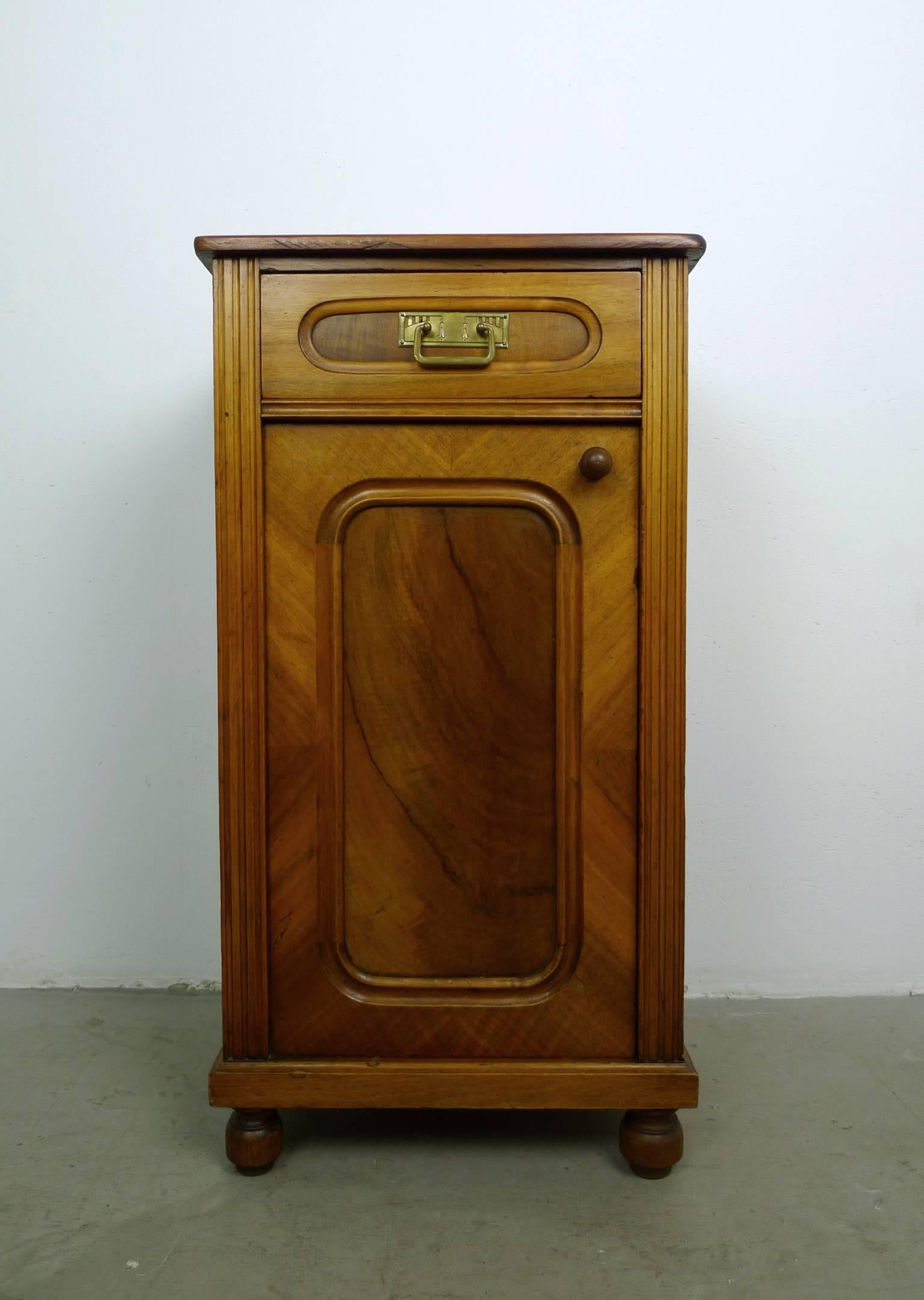 This small cabinet with drawer and door was produced in Germany, circa 1900 in the Gründerzeit style.
The softwood body is veneered in walnut. The front is framed by fluted fillets on the left and right. The body standing on four turned ball feet.