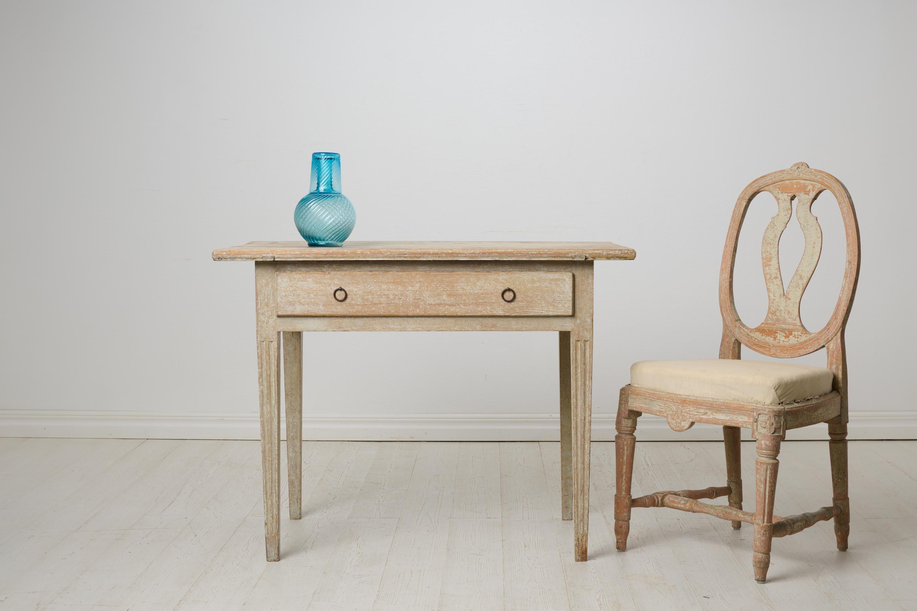 Gustavian antique country table from northern Sweden. The table is made by hand around 1820 in solid pine. Classic straight gustavian shape and straight tapered legs with flutes. One large centre drawer. Original old paint with distress after use.